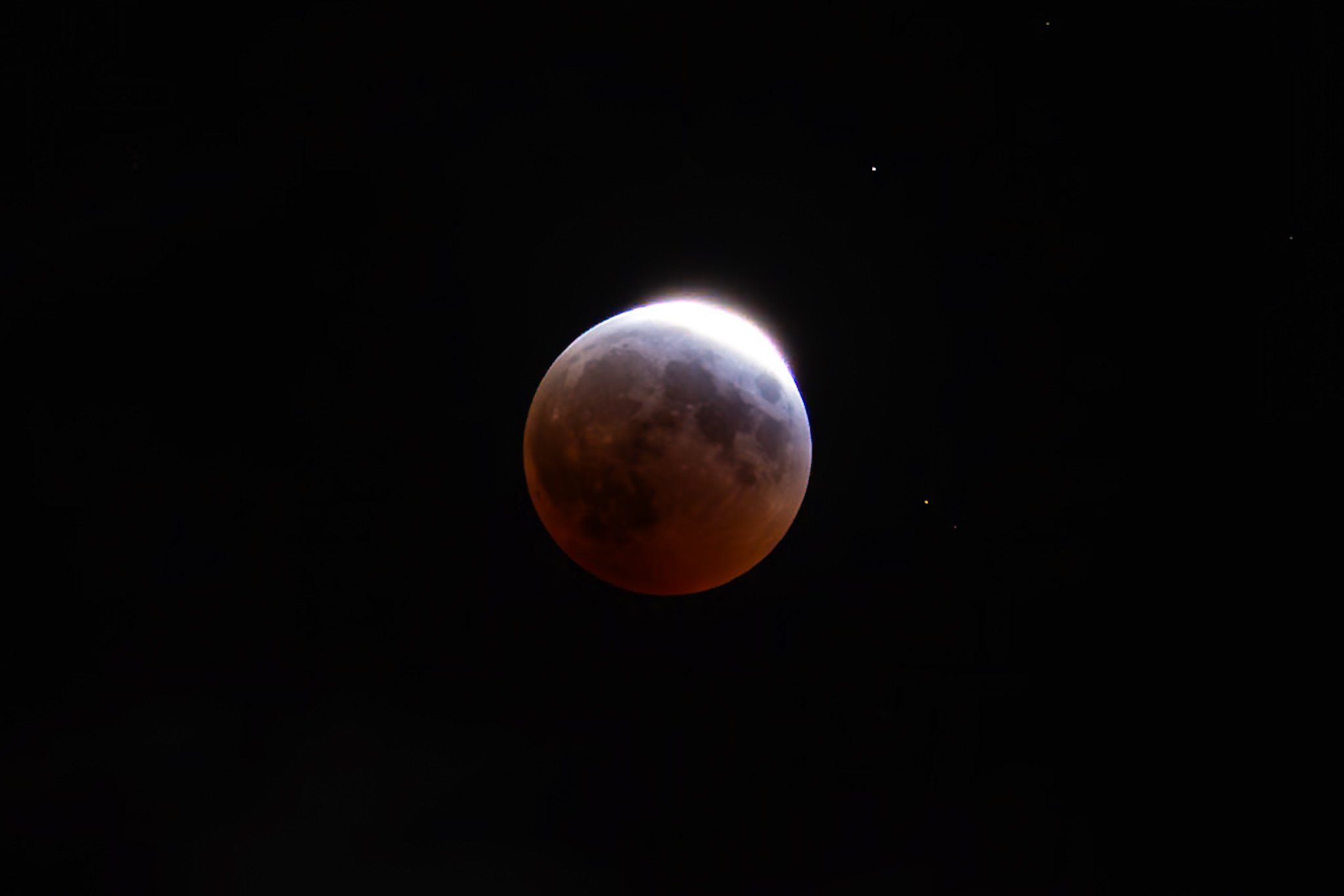 A lunar eclipse showing a blood moon with a reddish hue in the night sky.