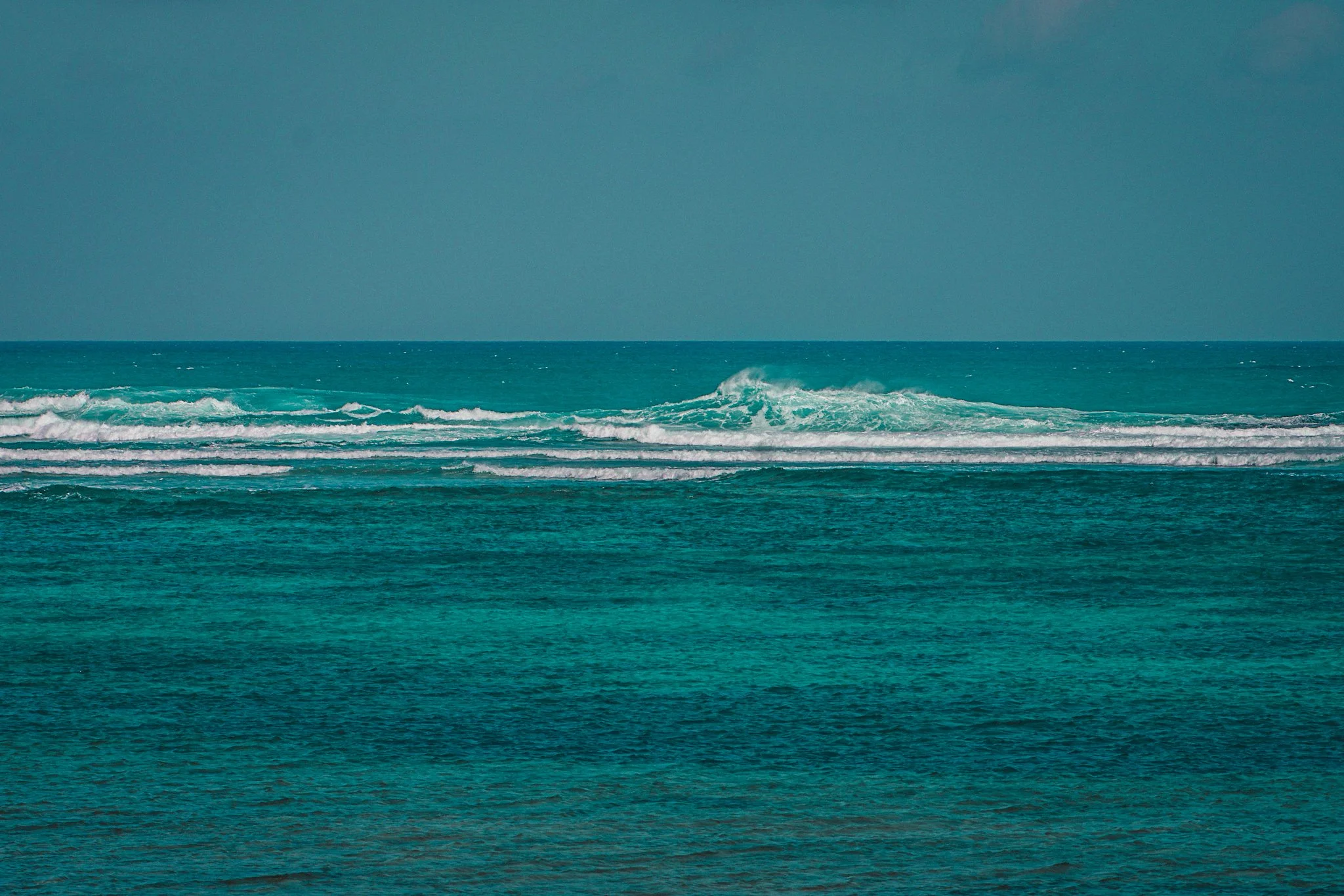 A calm ocean with gentle waves and a clear sky in the background.