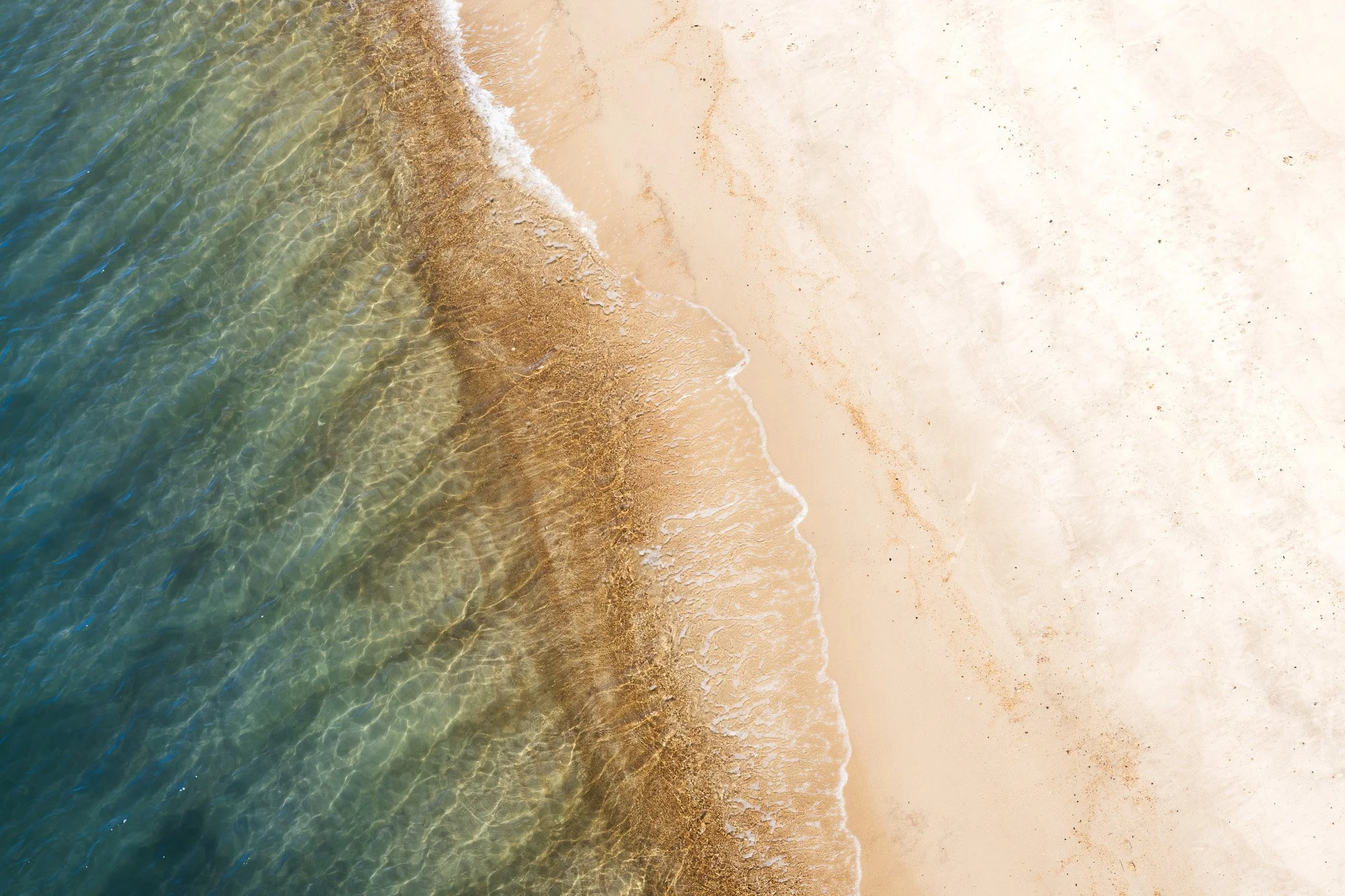 A beach with clear water and gentle waves lapping onto the sandy shore.