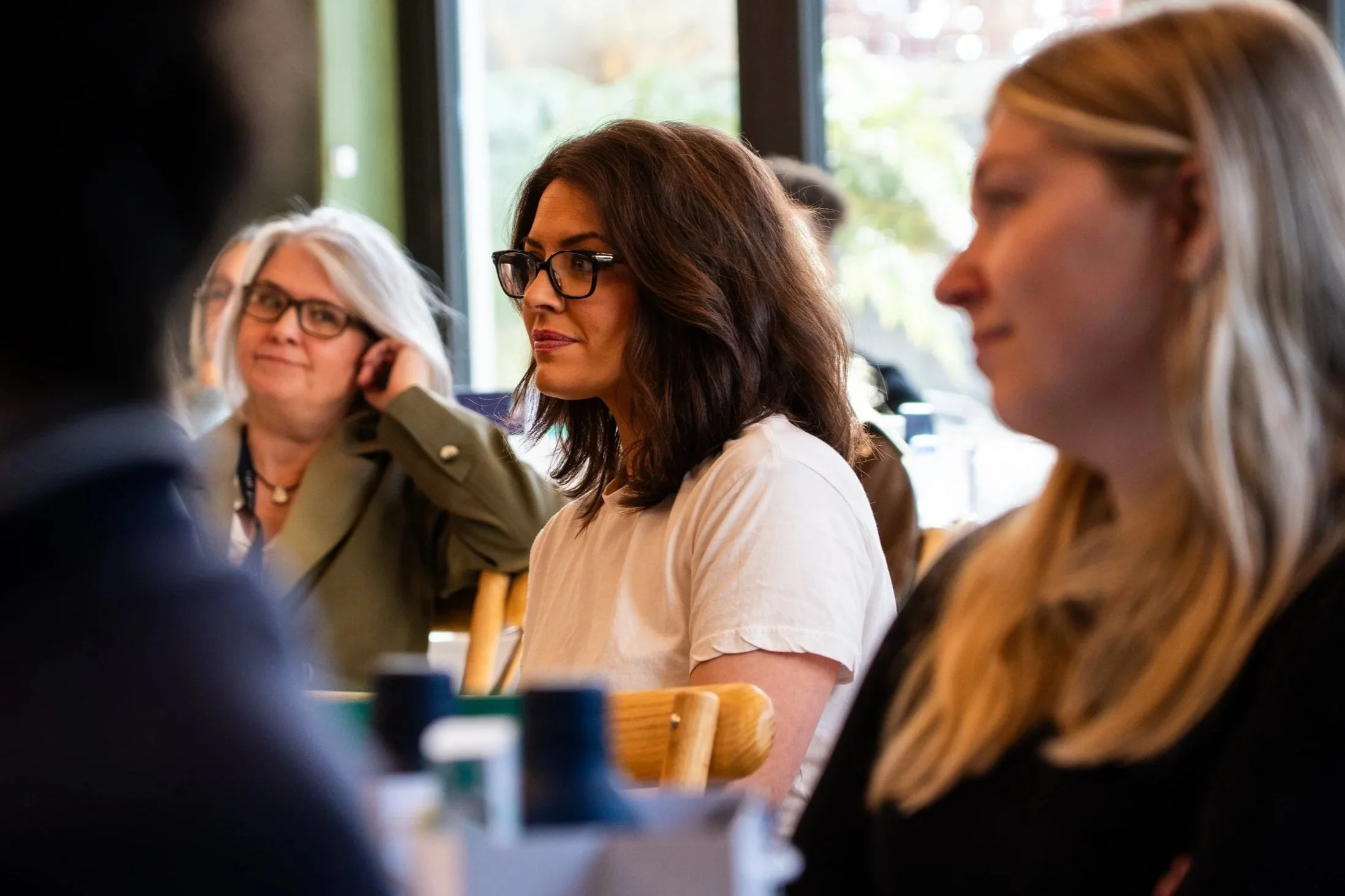 Group of women sitting at a table in a café, engaged in conversation.