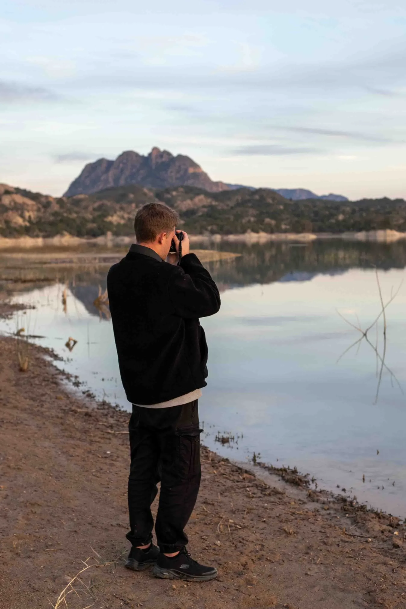 Cristian Pérez, fotógrafo en Murcia haciendo fotos en la naturaleza en un lago con montañas de fondo