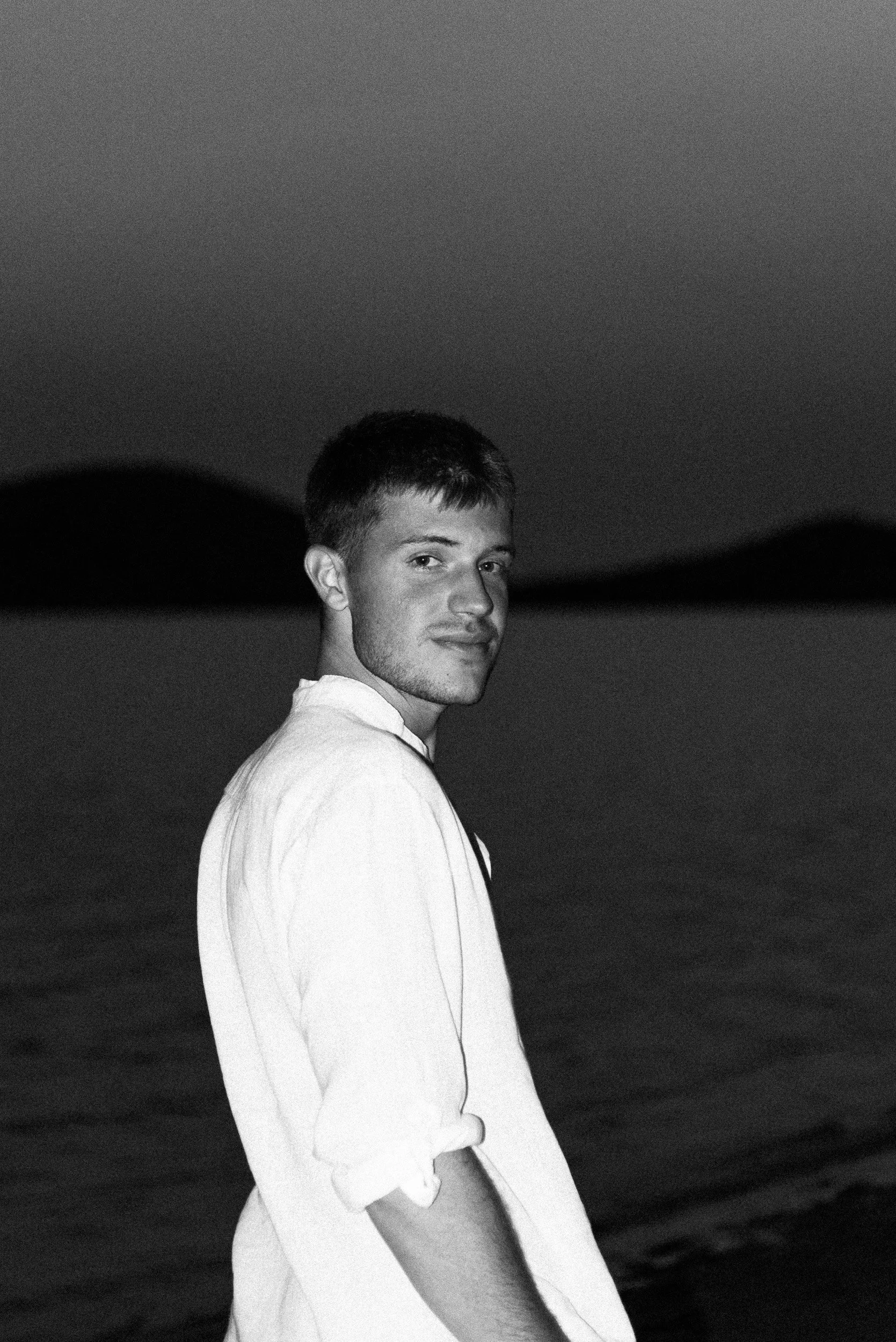Retrato de Cristian Pérez, fotógrafo, en la playa con luz de flash, en blanco y negro