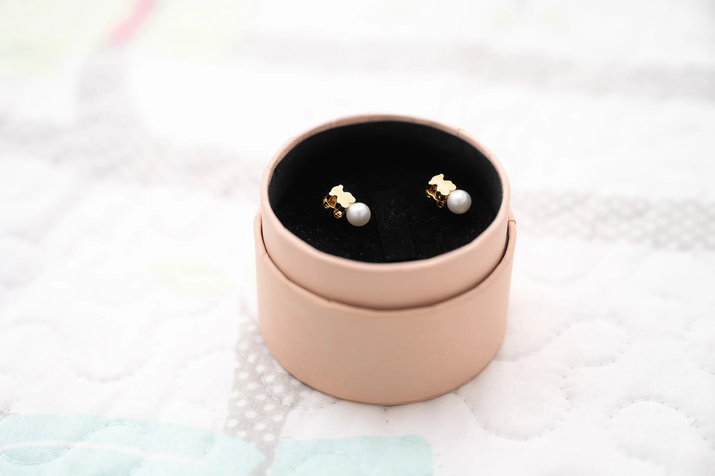 Aretes de perlas con base dorada en caja rosada.