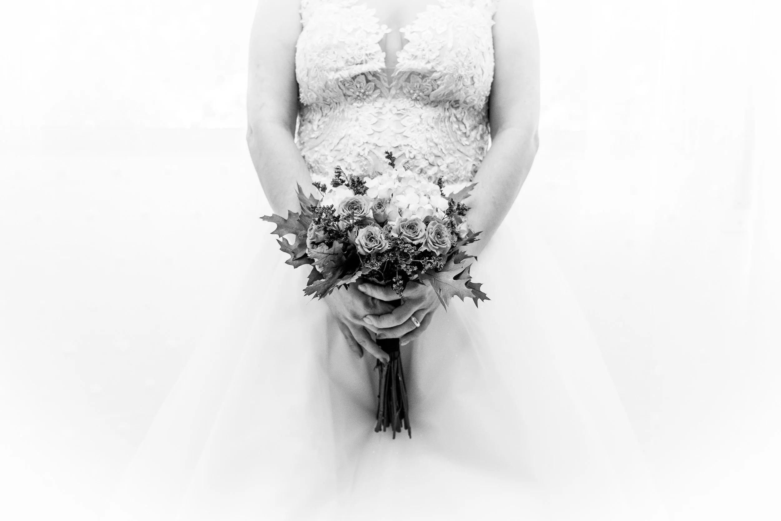 Una novia en vestido de novia blanco sosteniendo un ramo de flores.