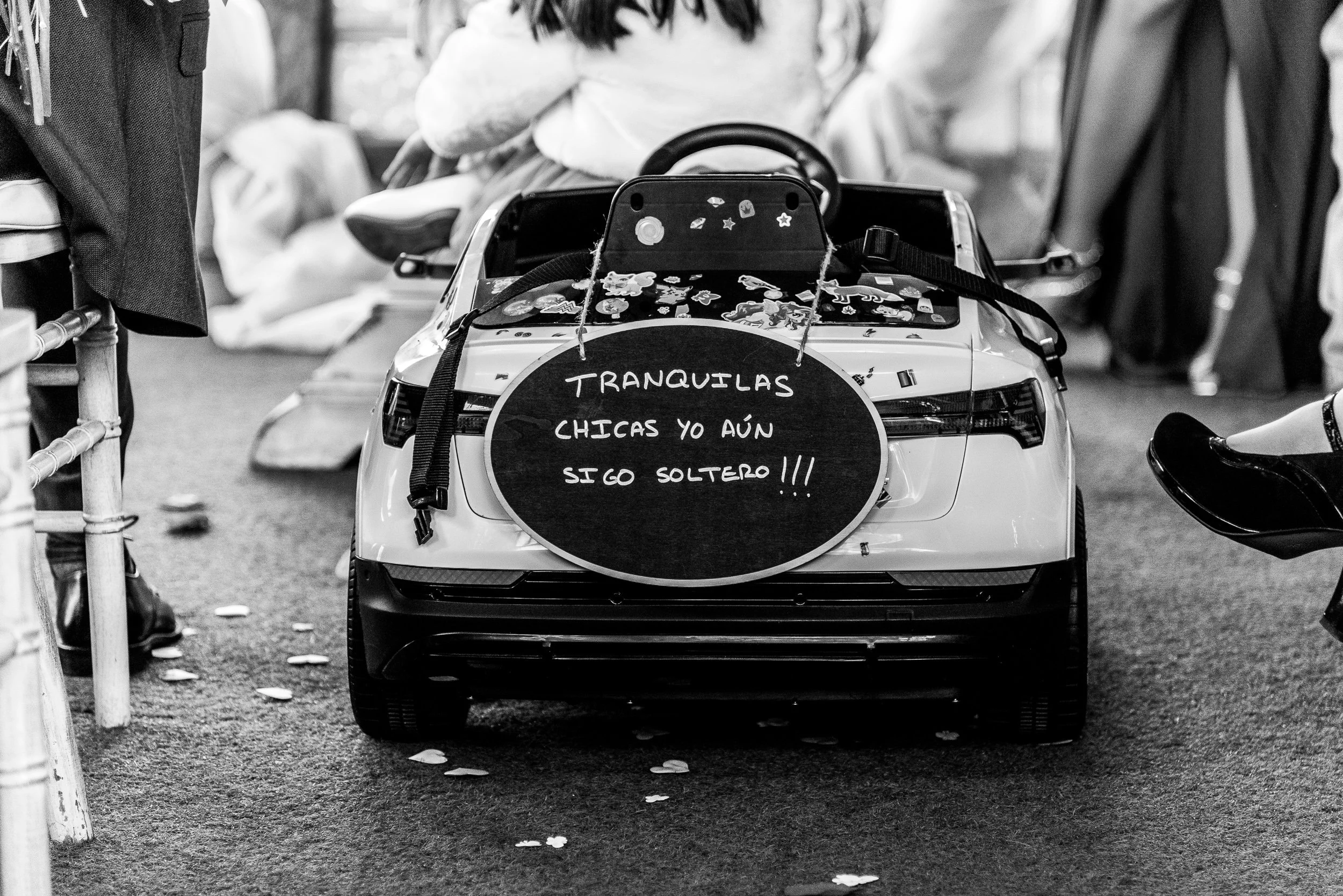 Coche pequeño decorado con pegatinas y confeti, con un cartel que dice: "Tranquilas chicas, aún sigo soltero".