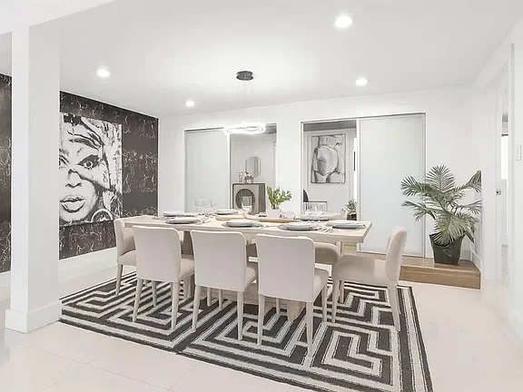 Modern dining room with white table and chairs, black and white geometric rug, large Marilyn Monroe portrait, and potted plant.