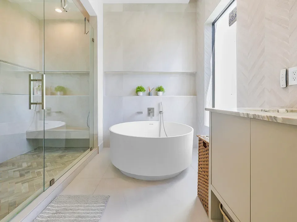 Modern bathroom with a freestanding bathtub, glass-enclosed shower, and a vanity with a marble countertop.
