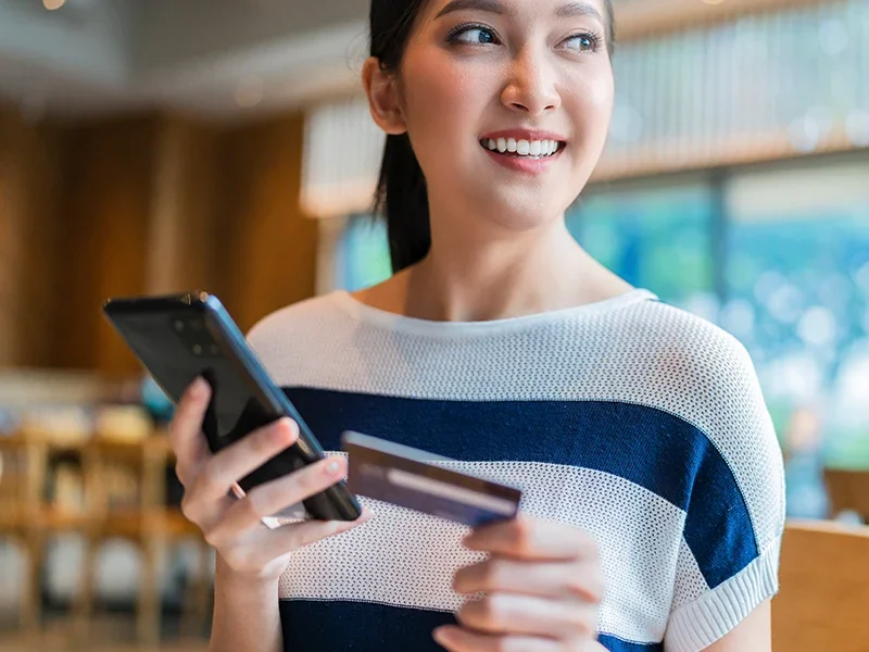 Young woman with a smartphone and credit card making a church donation.