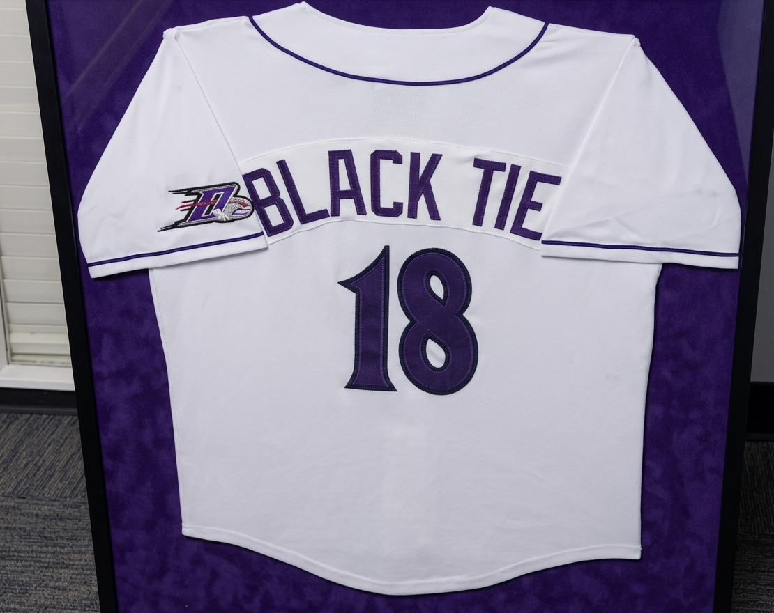 White sports jersey with purple accents displaying the words "BLACK TIE" and the number "18" on the back, with a logo on the sleeve.