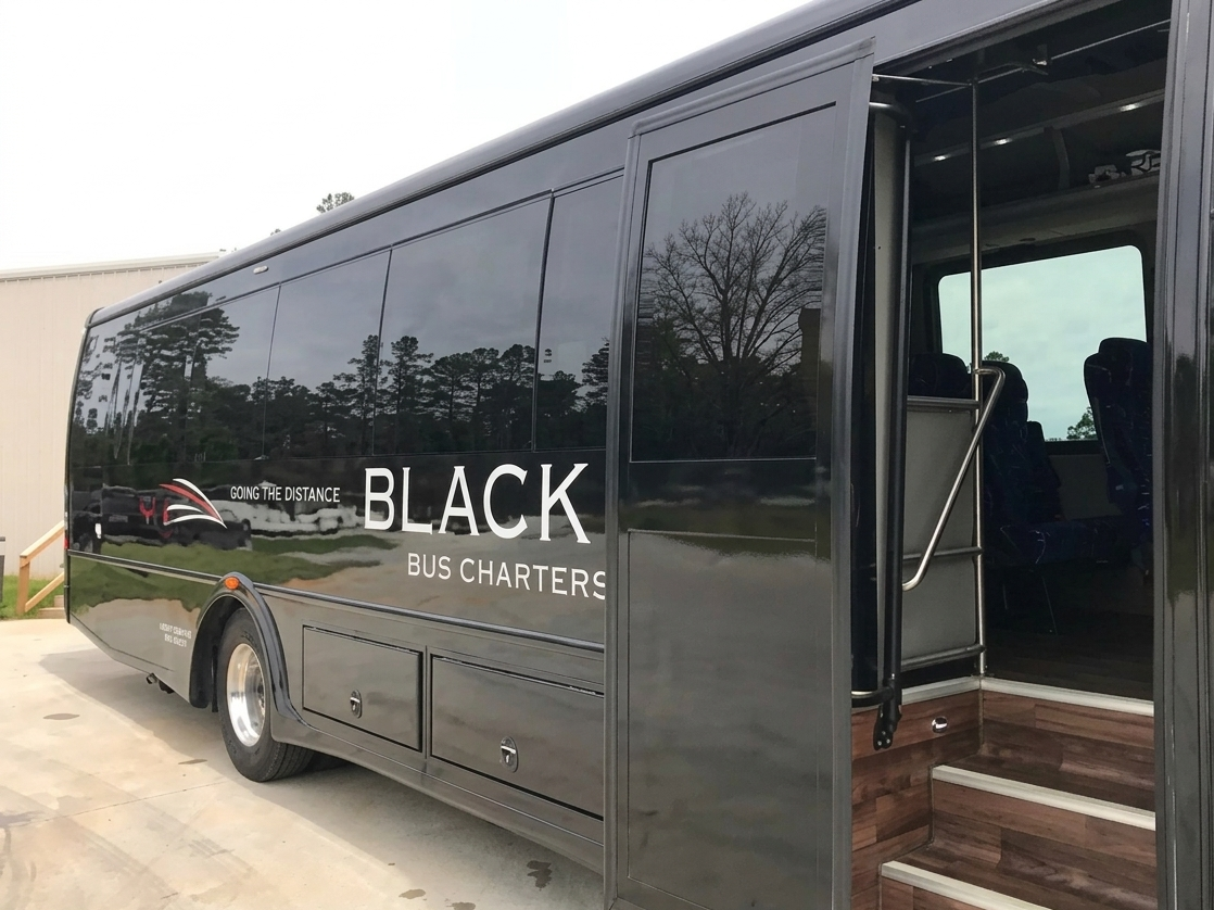 Black bus with logo and words 'Going the Distance Black Bus Charters,' parked outside with trees reflected on the side.