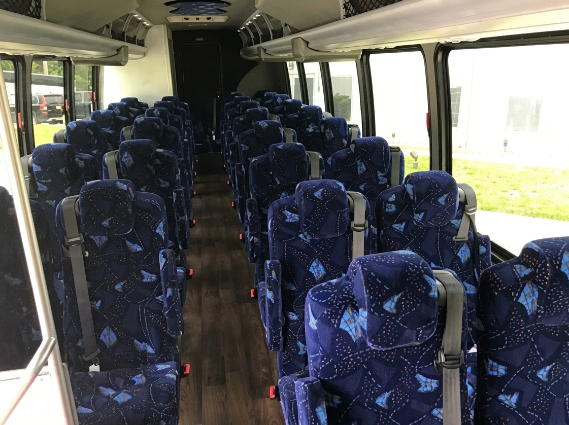 Interior of a bus with blue patterned seats and large windows.