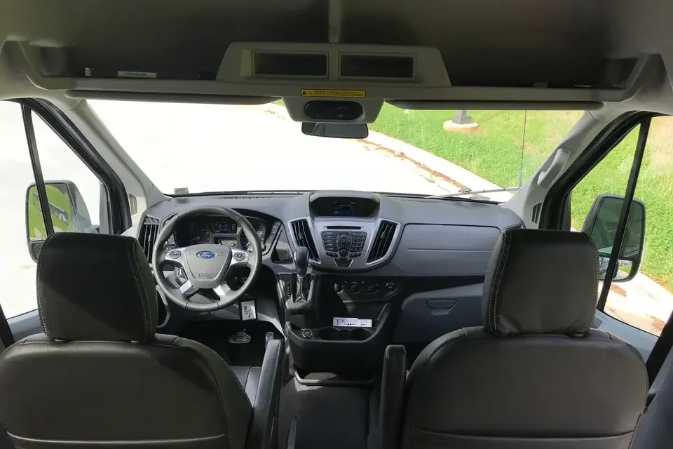 Interior view of a modern vehicle cabin showing the driver's seat, passenger seat, steering wheel, dashboard, and control panel.