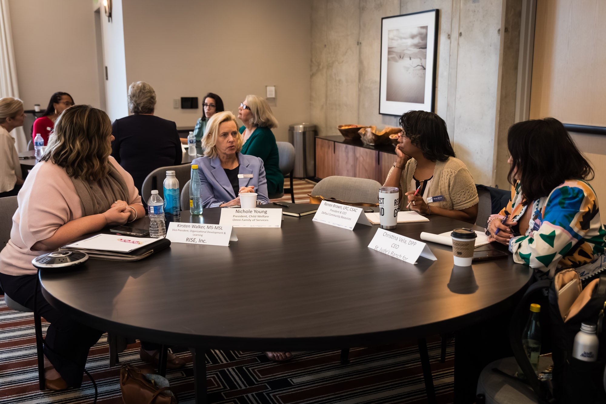 Four women sit around a round table in a meeting room, engaged in discussion about * career opportunities in human services.