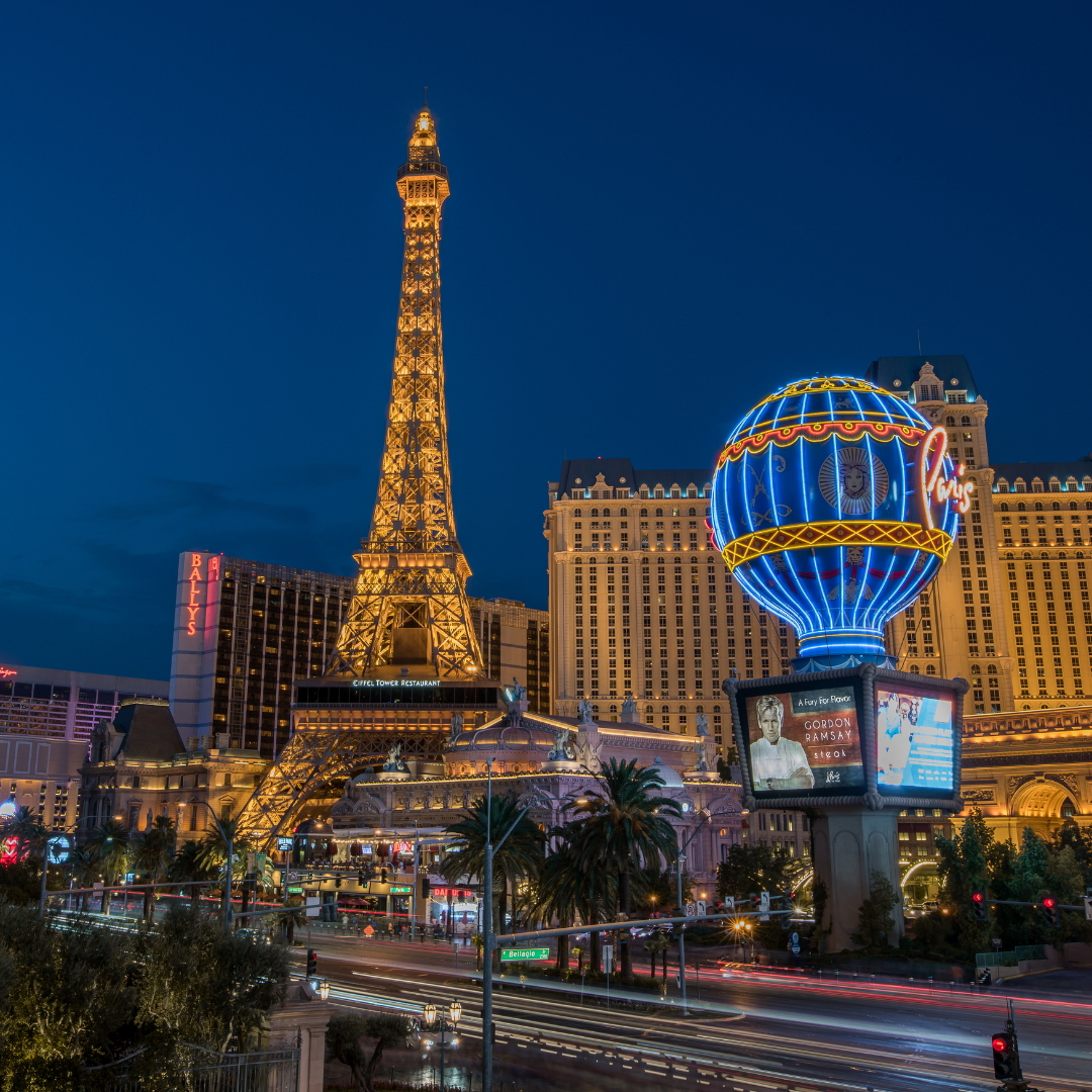 Paris Las Vegas hotel and casino with illuminated Eiffel Tower replica and neon Paris balloon at dusk showcasing the location and accommodations of FFTA.