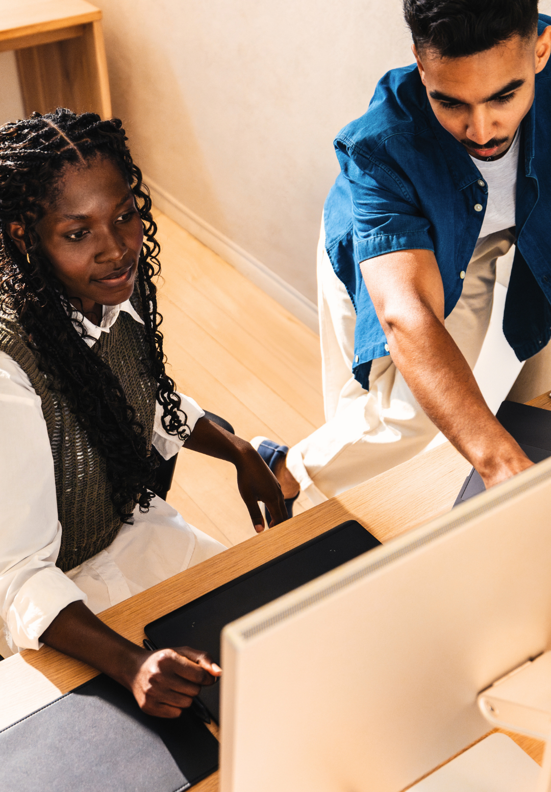 Two people work together on child welfare leadership at a desk, looking at a computer screen, with one person pointing at the monitor.