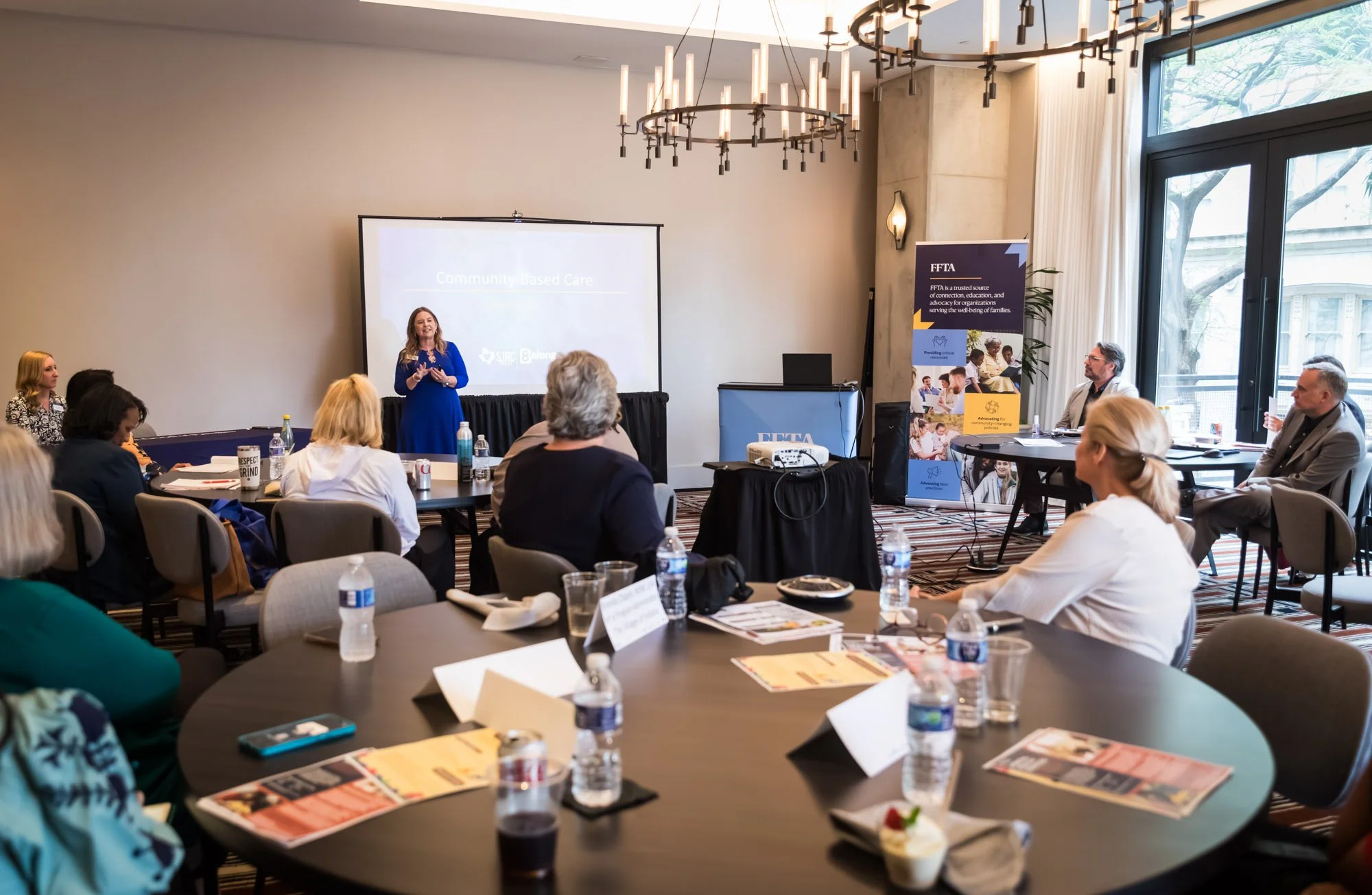 A woman speaks to an audience about * family-serving organization membership benefits.