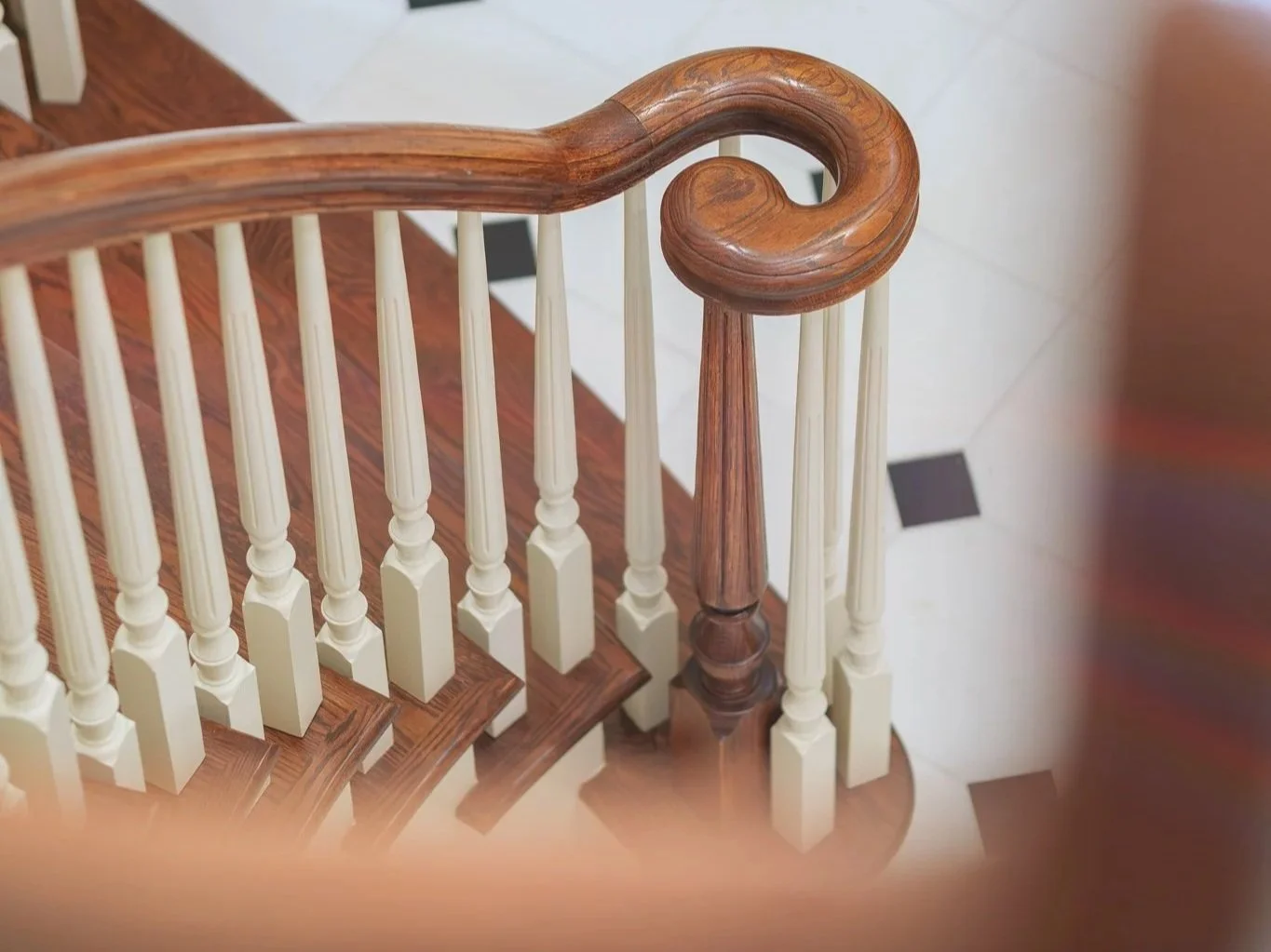 Close-up of a wooden staircase handrail and spindles, viewed from above.