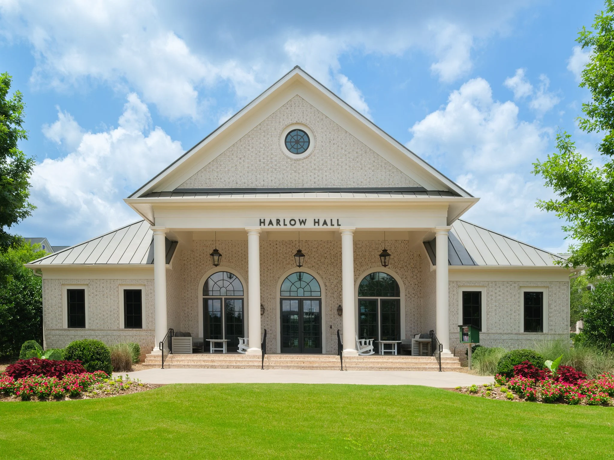 Front view of Harlow Hall, a brick building with a triangular roof. Real Estate Photography | Alpharetta | Milton | John's Creek | Buckhead | Atlanta | Drone | Video | Media | Luxury | Harlow | Empire Homes | Architecture photography | Interior Desig