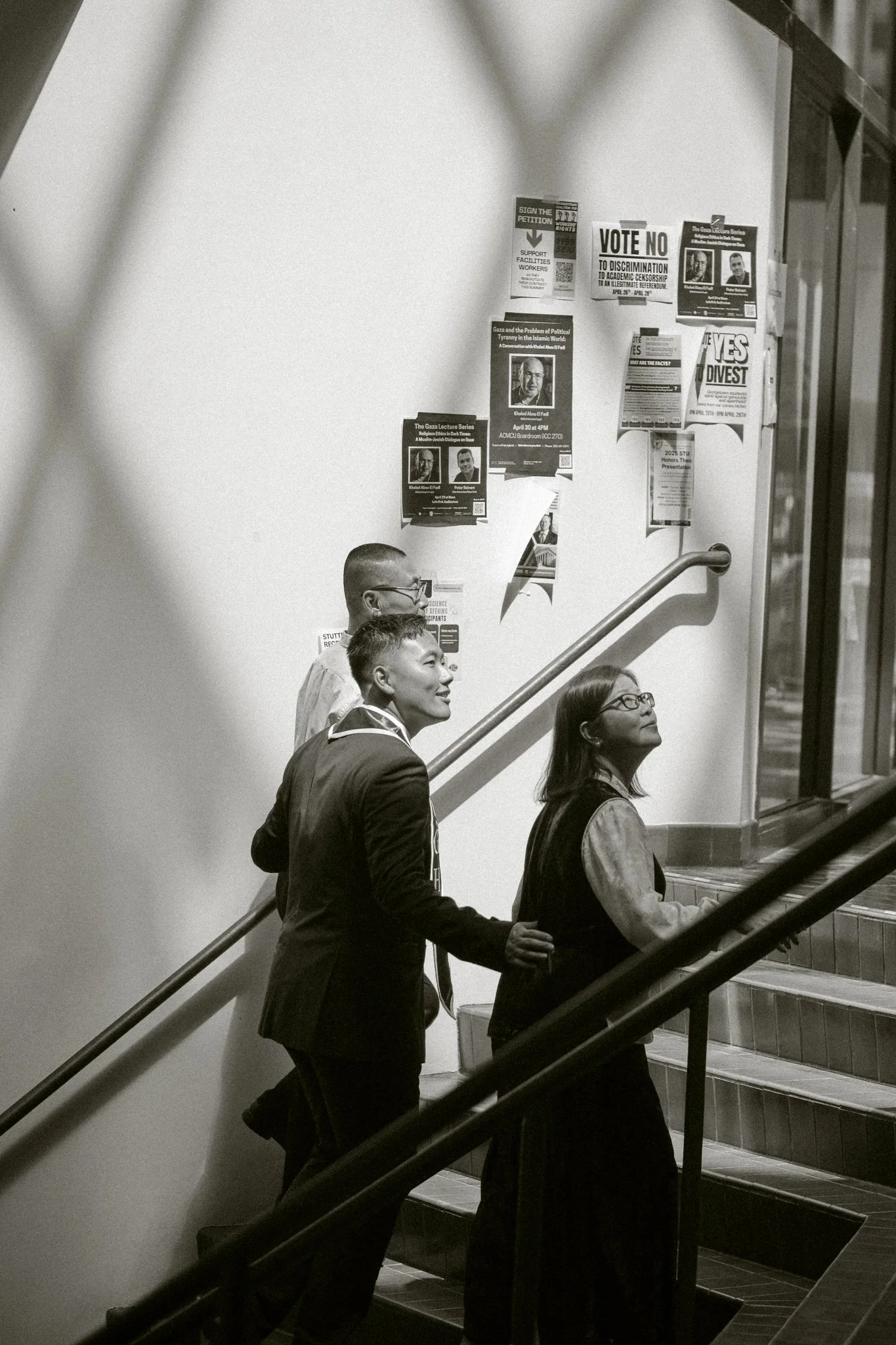 People ascending stairs in an indoor setting with posters on the wall