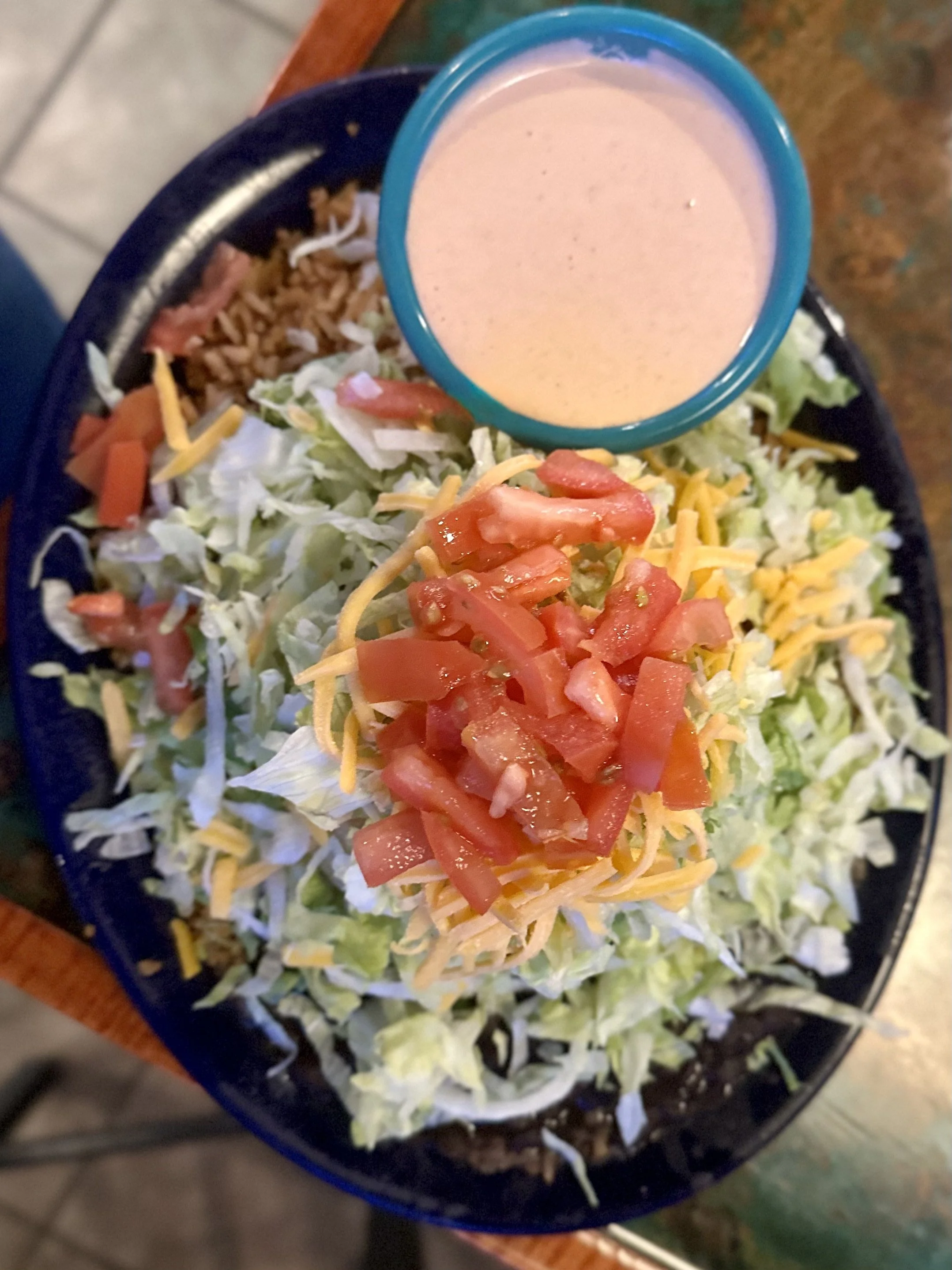 puffy taco, choice of protein, topped with lettuce, tomato, cheese, spanish rice and black beans on the side. house dressing is a must