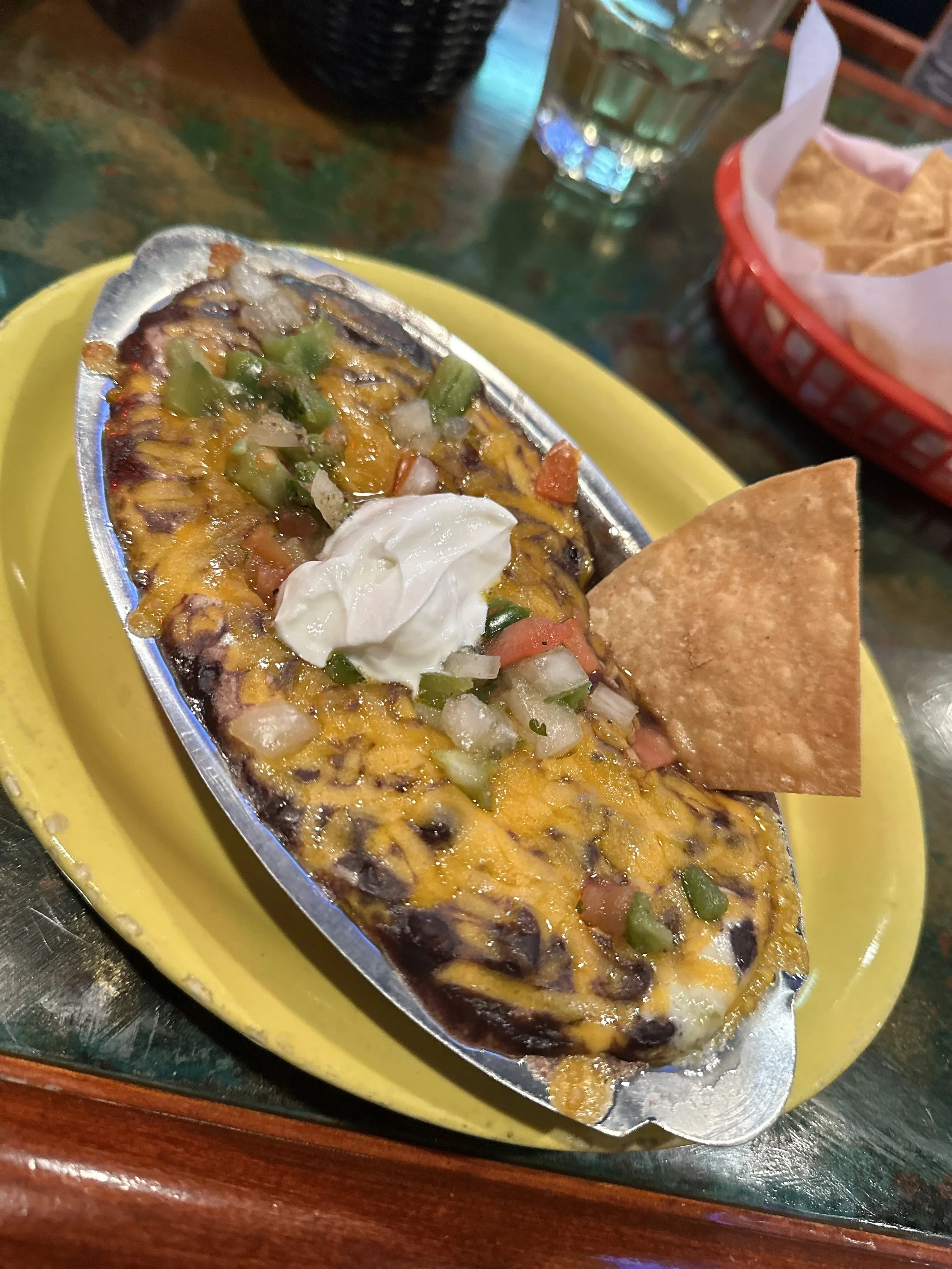 black bean dip layered with cheese, onions, pico de gallo, black beans, and sour cream