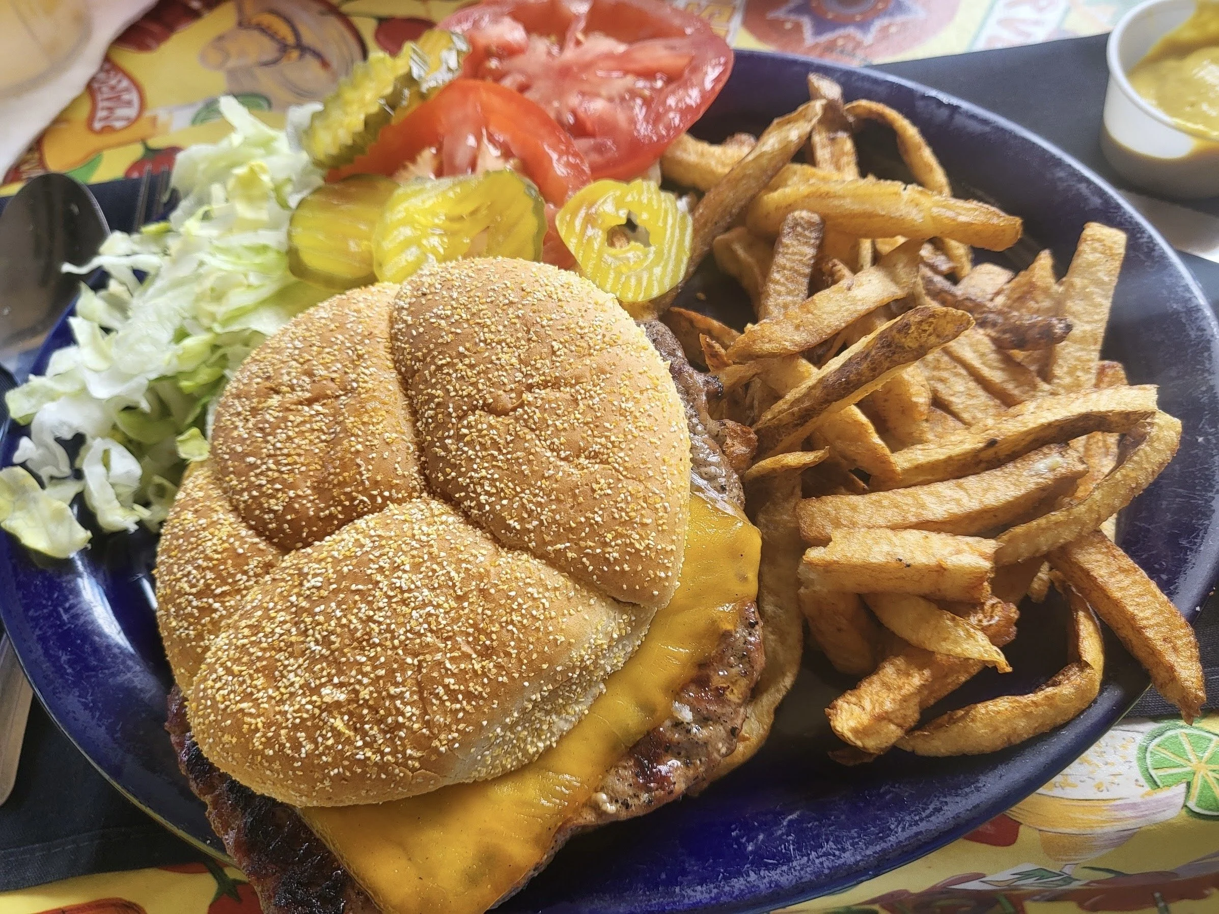 mesquite grilled hamburger with cheddar cheese, hand cut fries, lettuce, tomatoe, pickles on the side