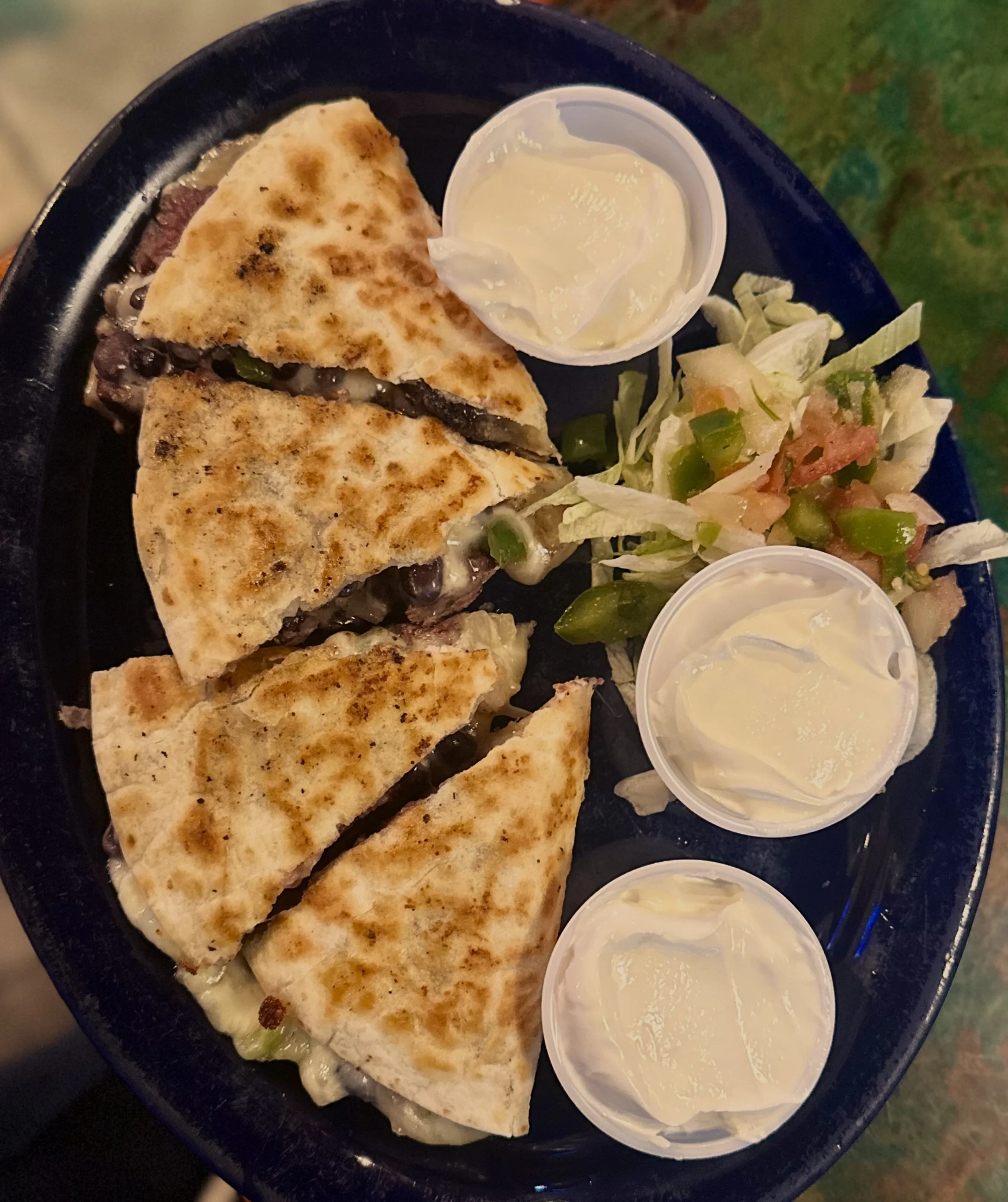Quesadilla stuffed with pepper jack cheese, protein, black beans, onions served with sour cream