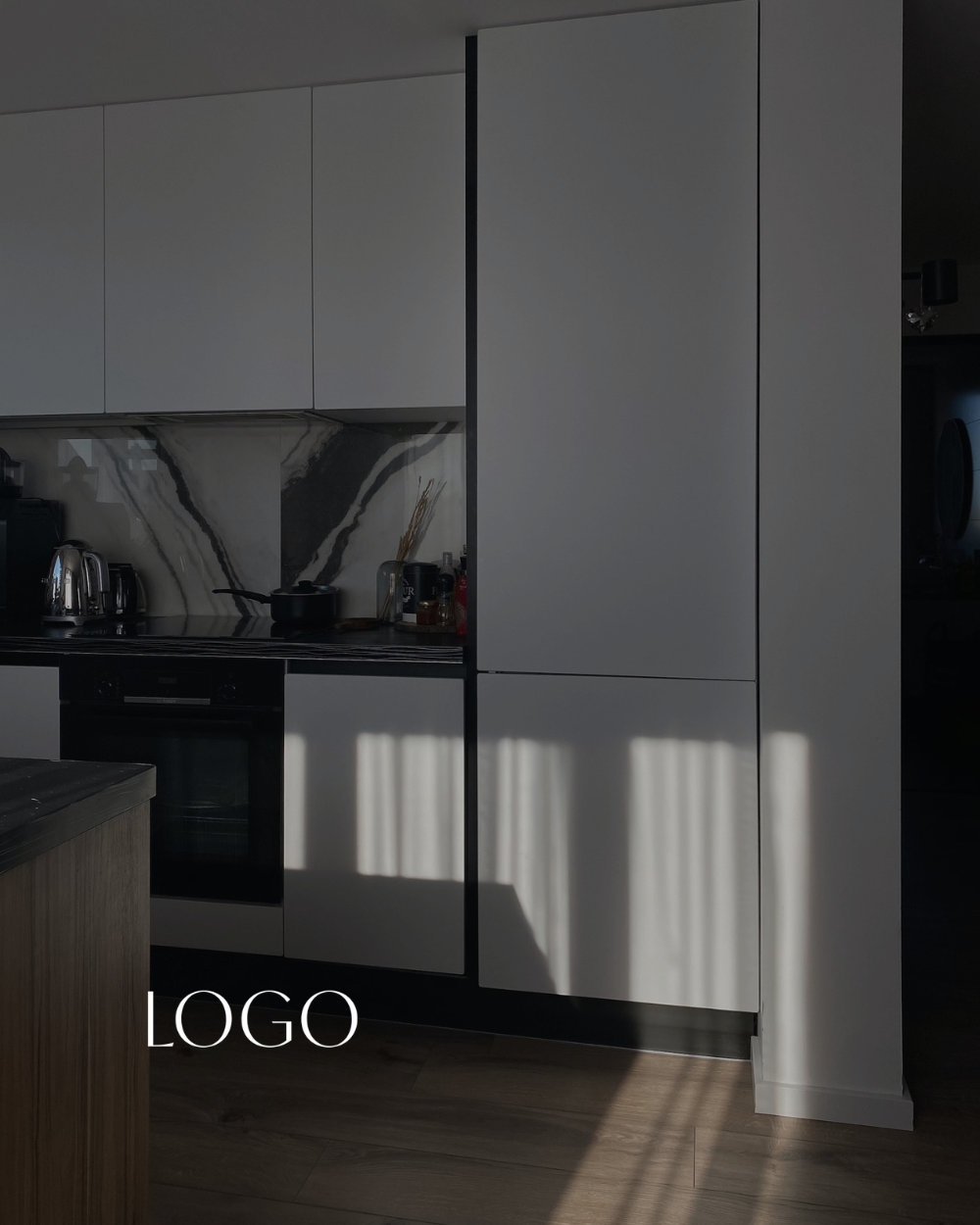 Modern kitchen with white cabinets, black marble backsplash, and a wooden floor. Shadows from window blinds are cast on the cabinets, and there is a placeholder for a logo in the bottom left corner.