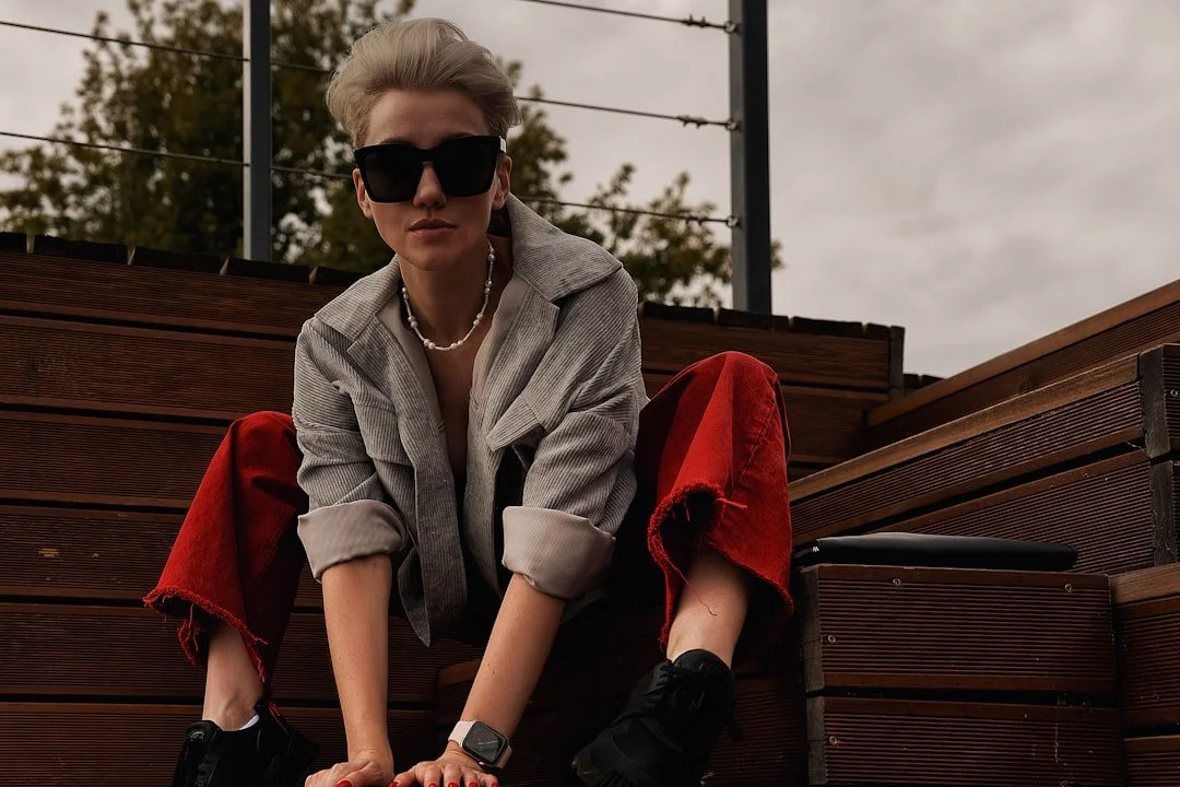 woman crouching outside with sunglasses and red pants