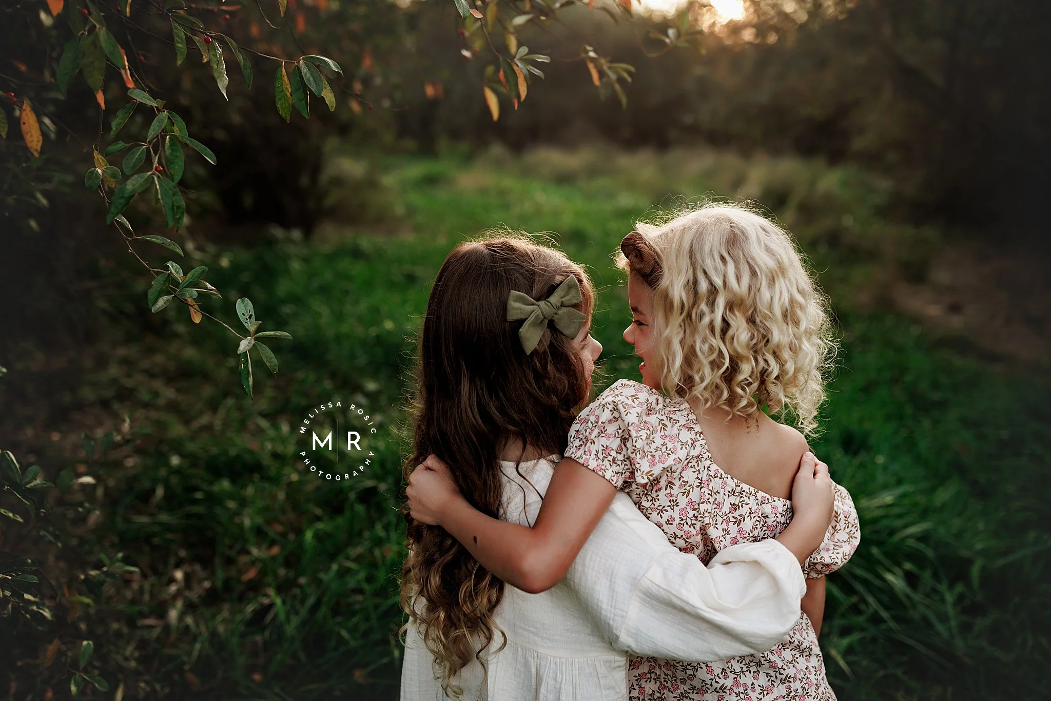 two young girls standing with arms wrapped around each other