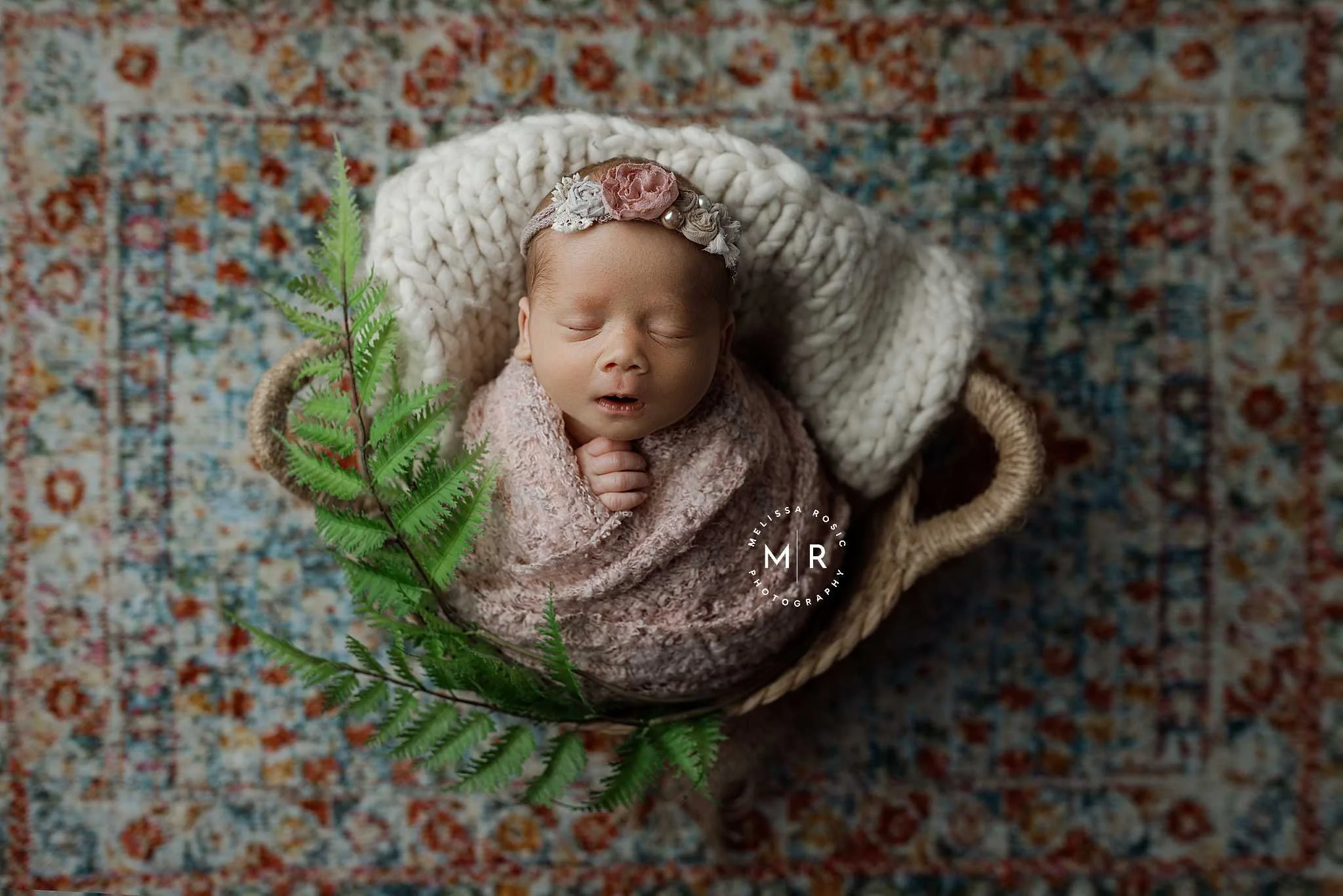 baby wrapped and in a basket on patterned floor