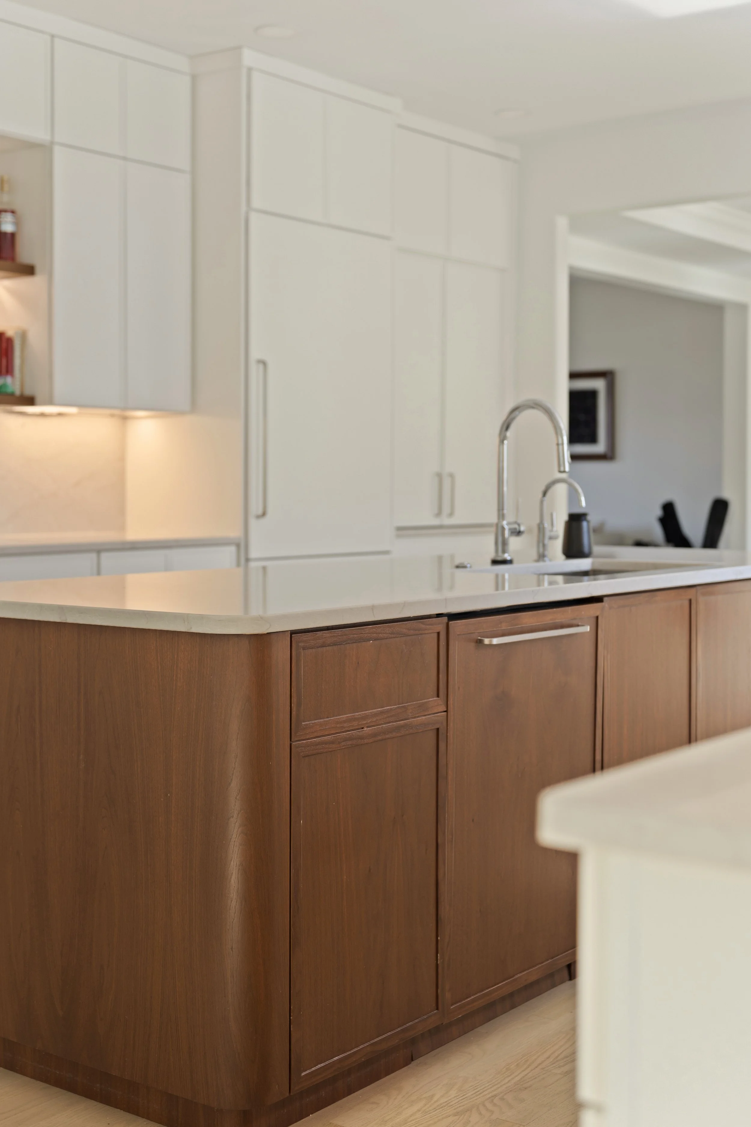 Kitchen with white upper cabinets, wood lower cabinets, a marble countertop, and a sink with a faucet.