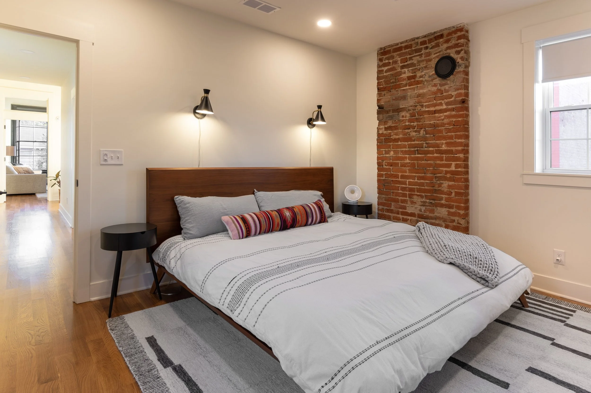 Primary bedroom with exposed brick accent wall in historic Covington Kentucky remodel by Shade Tree Homes