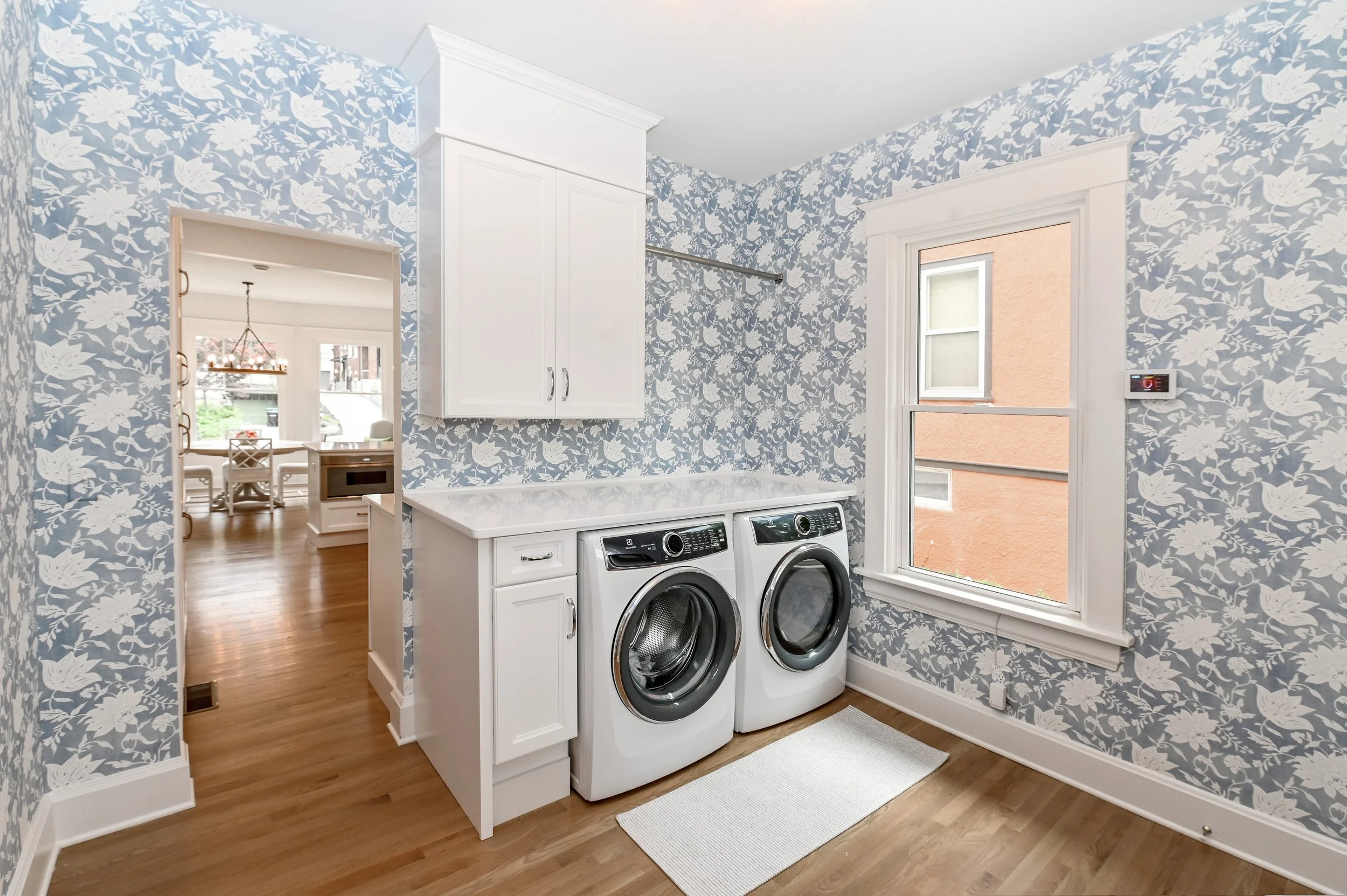 Custom laundry room with designer wallpaper and built-in cabinetry by Shade Tree Homes
