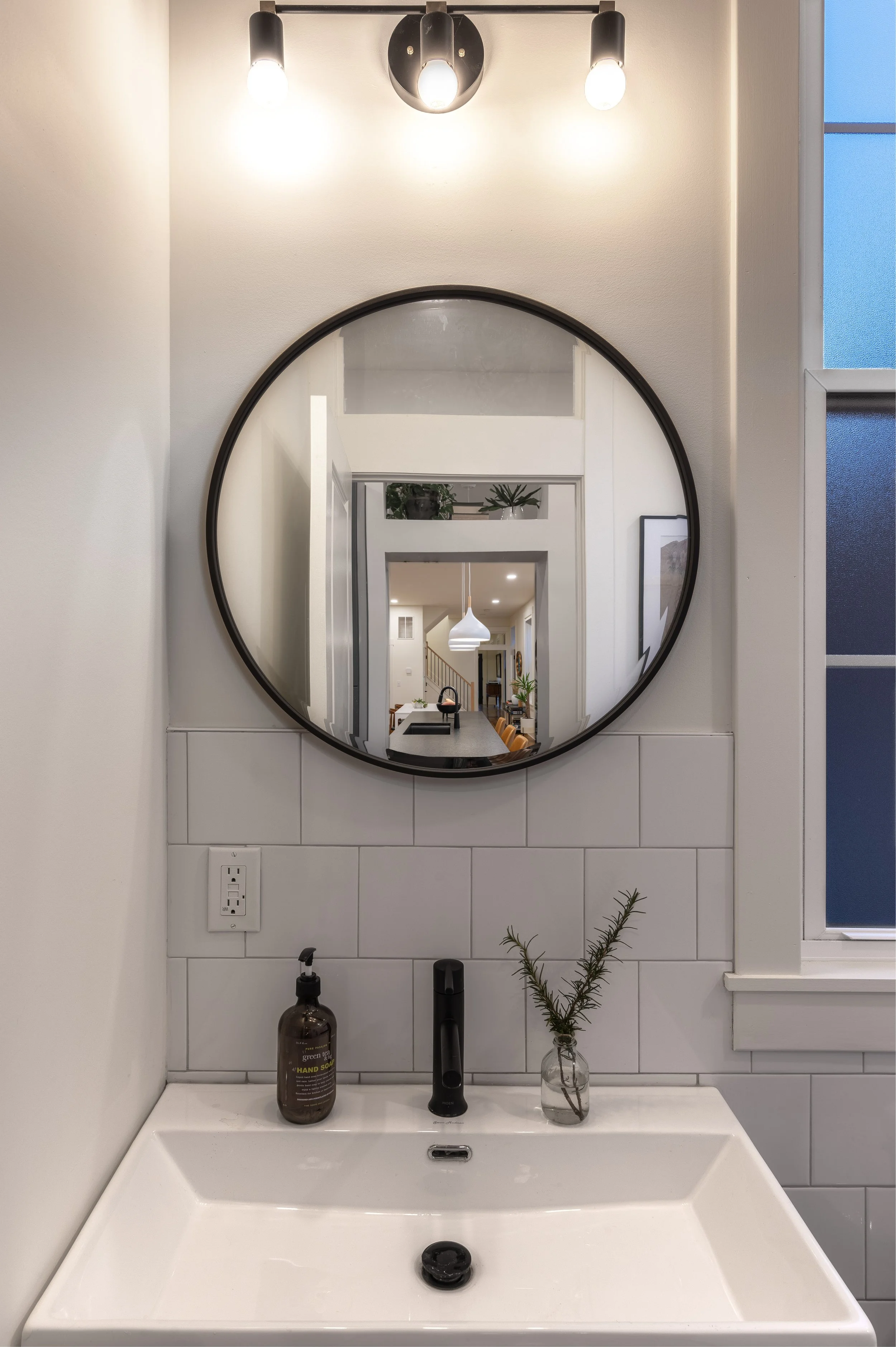Remodeled bathroom with round mirror and custom vanity in Covington Kentucky by Shade Tree Homes