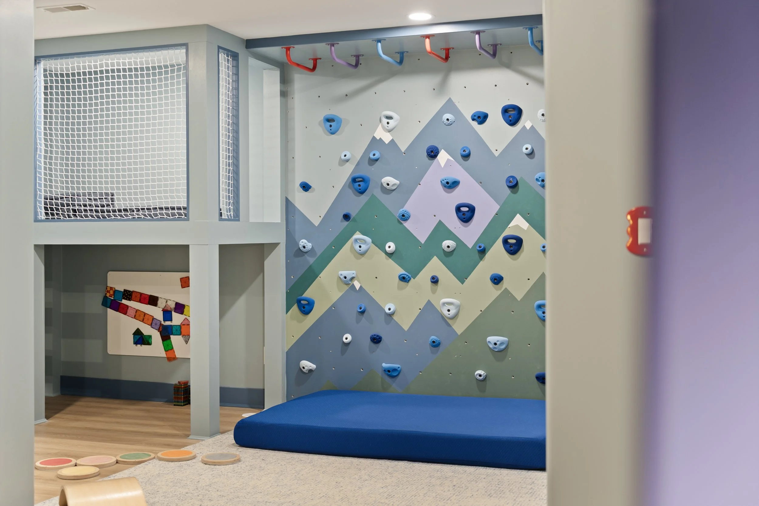 Custom playroom with climbing wall and kids play space by Shade Tree Homes