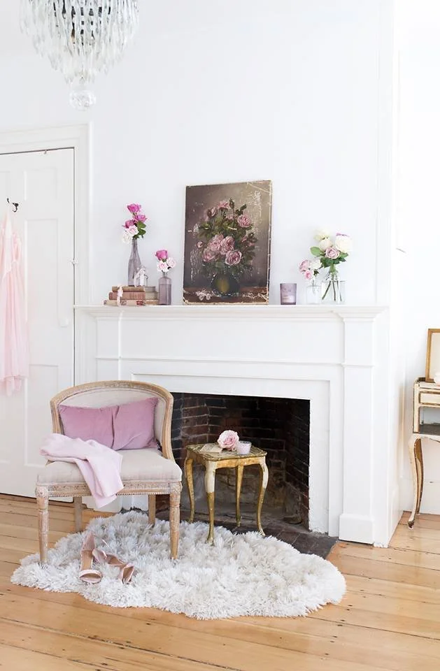  The home of Jo-Anne Coletti with a white fireplace mantel decorated with pink and white flowers in vases and a painting of pink roses.