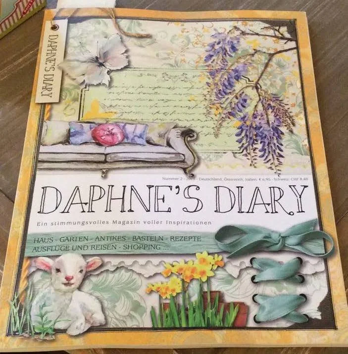 Decorative cover of a magazine titled "Daphne's Diary" featuring illustrations of a sofa with a pillow, flowers, a lamb, and other decorative elements.