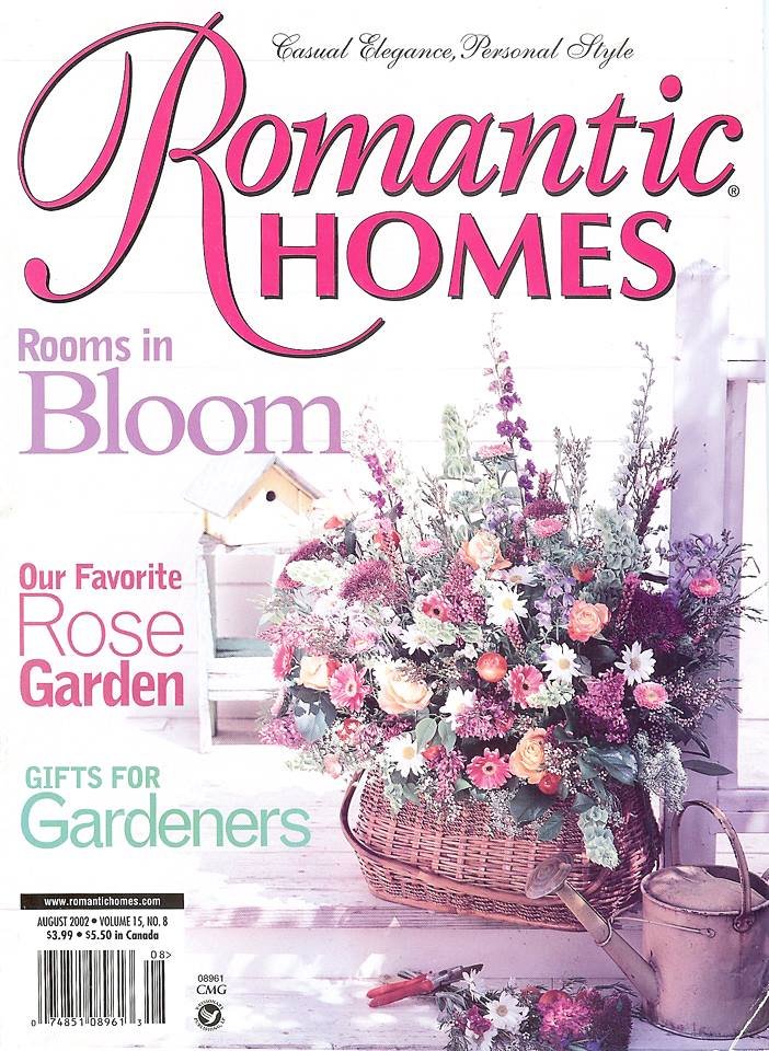  Jo-Anne Coletti featured in A magazine cover titled. Cover page of Romantic Homes magazine featuring a large bouquet of colorful flowers in a wicker basket, with gardening tools and a birdhouse in the background, dated August 2002.