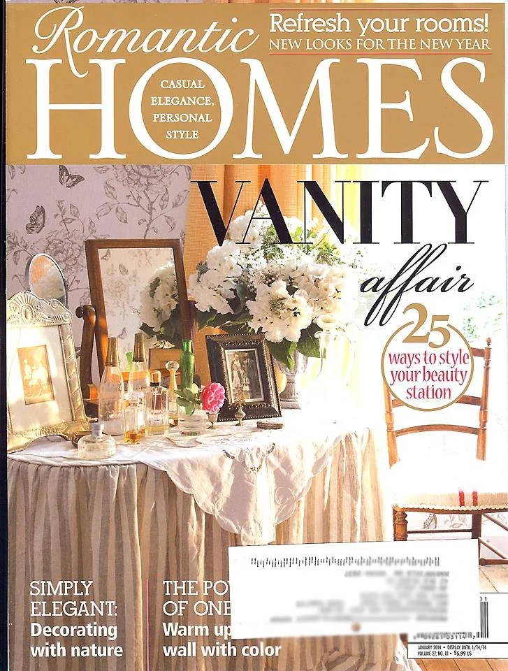 Artist and designer, Jo-Anne Coletti featured in A magazine cover titled "Romantic Homes" Cover of Romantic Homes magazine featuring a decorated table with flowers, picture frames, and decorative bottles, and a wooden chair in a bright room.