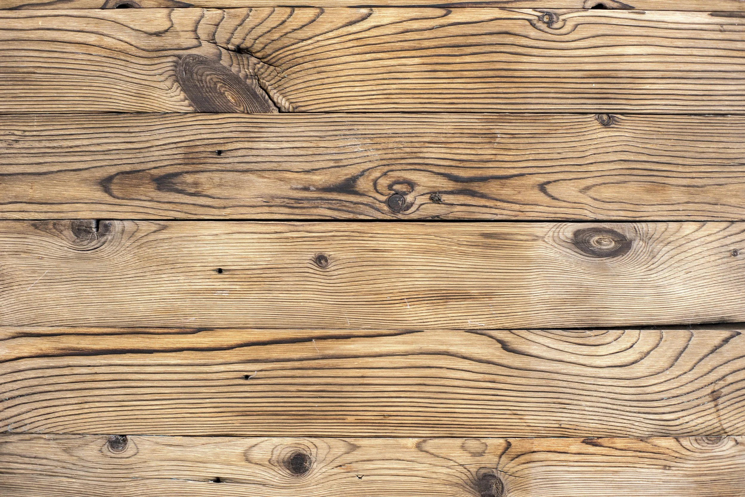 Close-up of wooden planks with visible grain patterns, knots, and small holes.