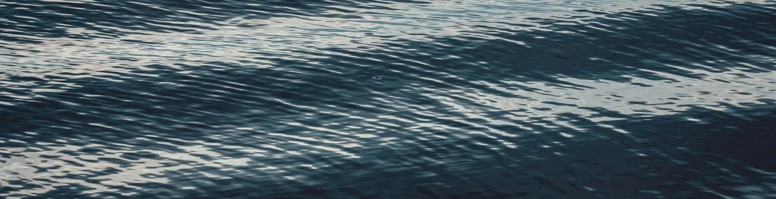 Close-up view of the surface of a body of water with gentle ripples reflecting light