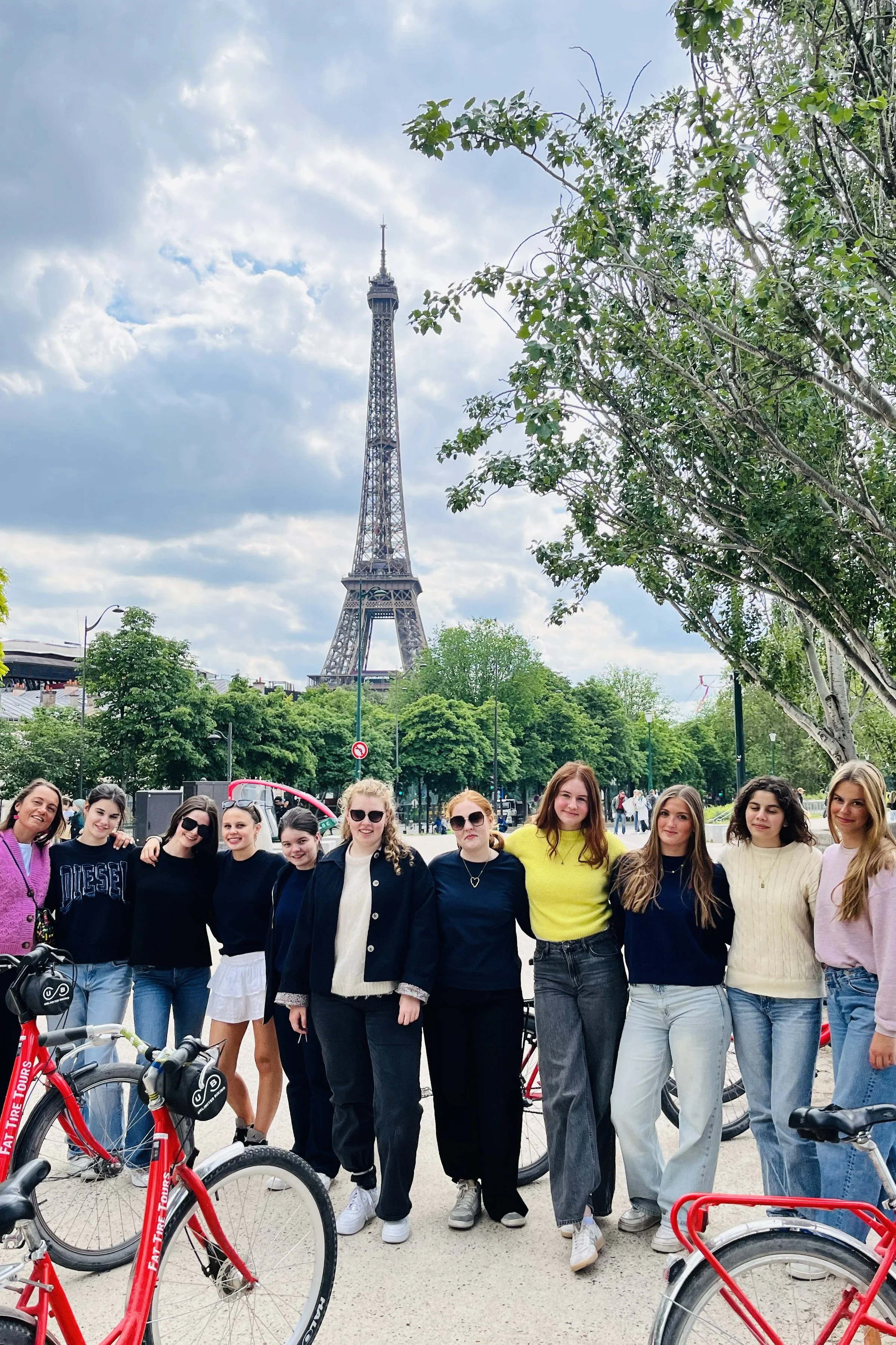 Group of women in front of the Eiffel Tower in Paris with red bikes