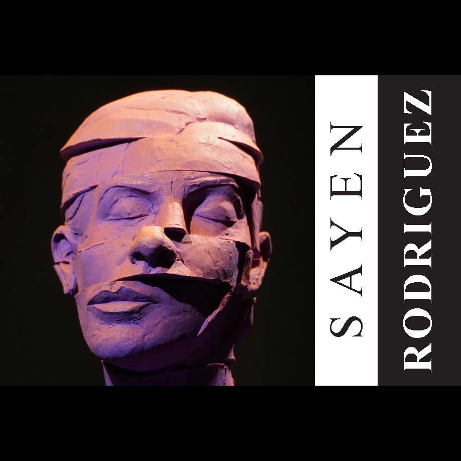 A sculpture of a person's face with closed eyes, made of layered material, with some broken or cracked parts.