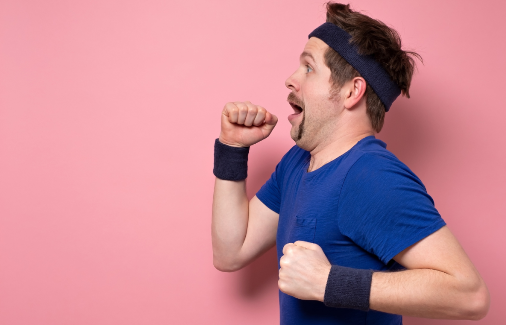 goofy man wearing sweatbands pretending to run against a pink background