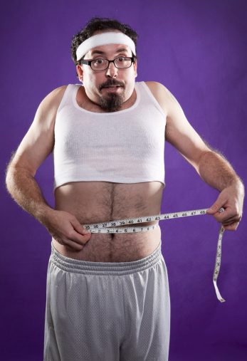 man sucking in while measuring his waist circumference
