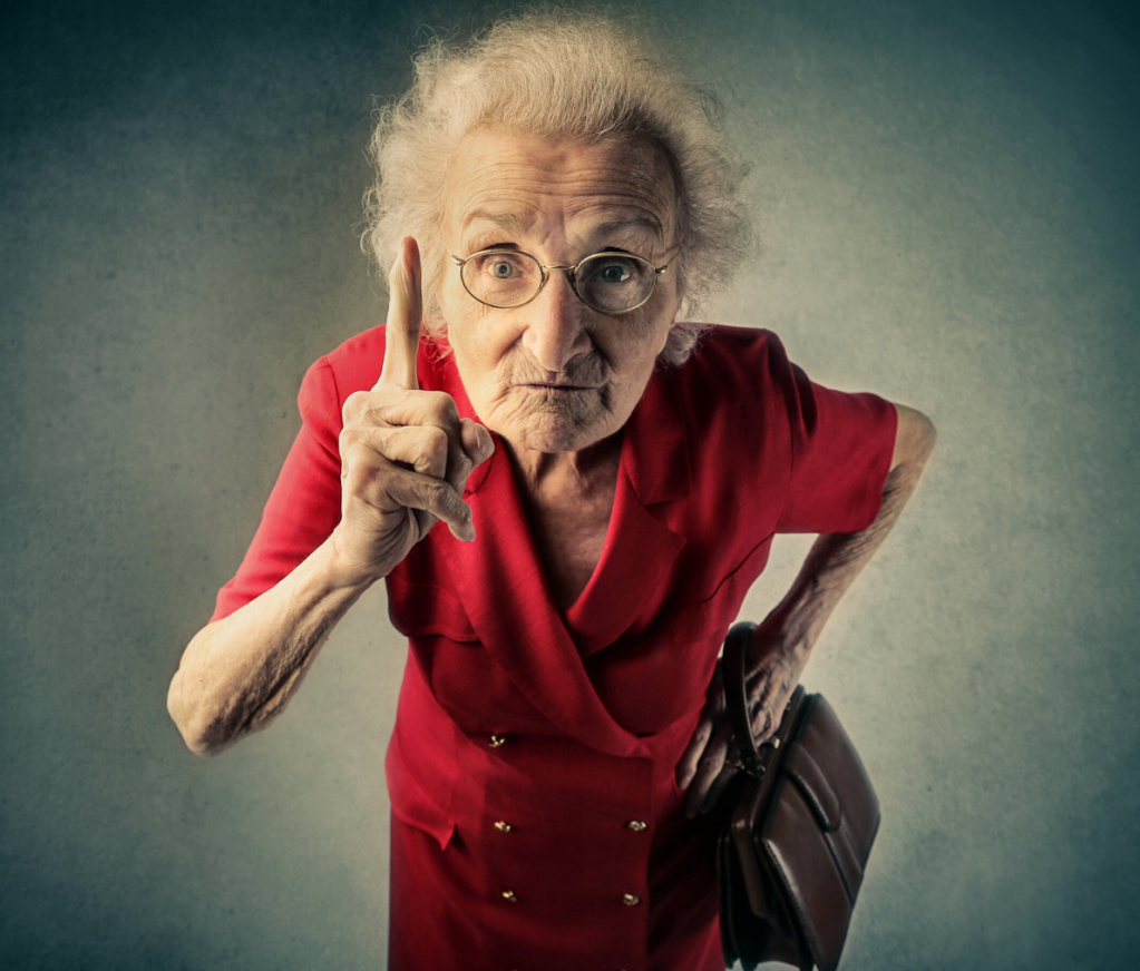 old lady in a red dress looking at the camera and pointing her finger at you