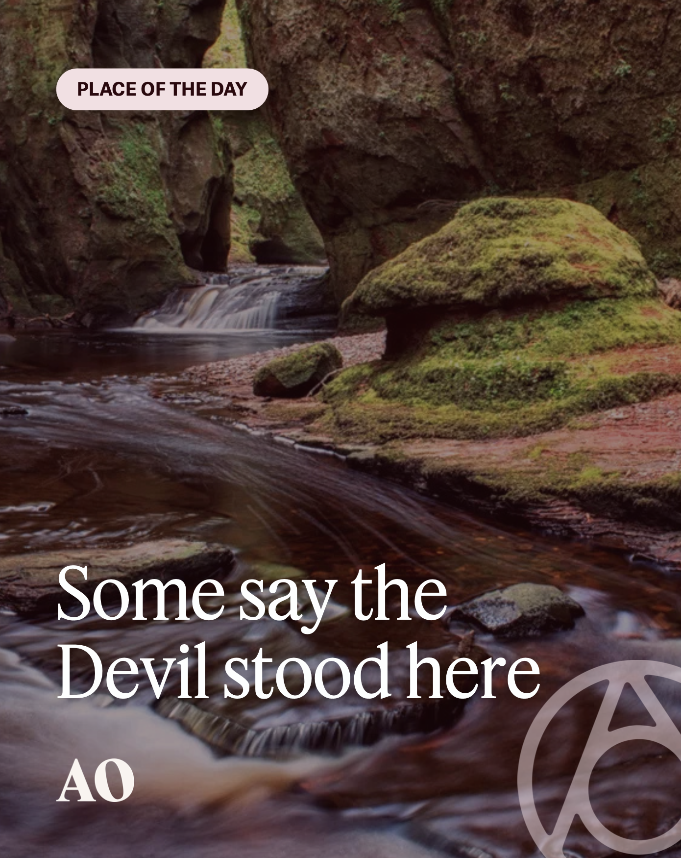 A river flowing through a rocky, moss-covered canyon with a small waterfall in the background. The scene is natural and serene, with a label saying 'Place of the Day' and text that reads 'Some say the Devil stood here.'