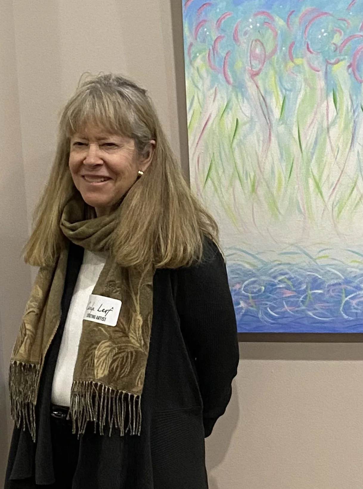 photo of carolyn leaf standing by one of her paintings