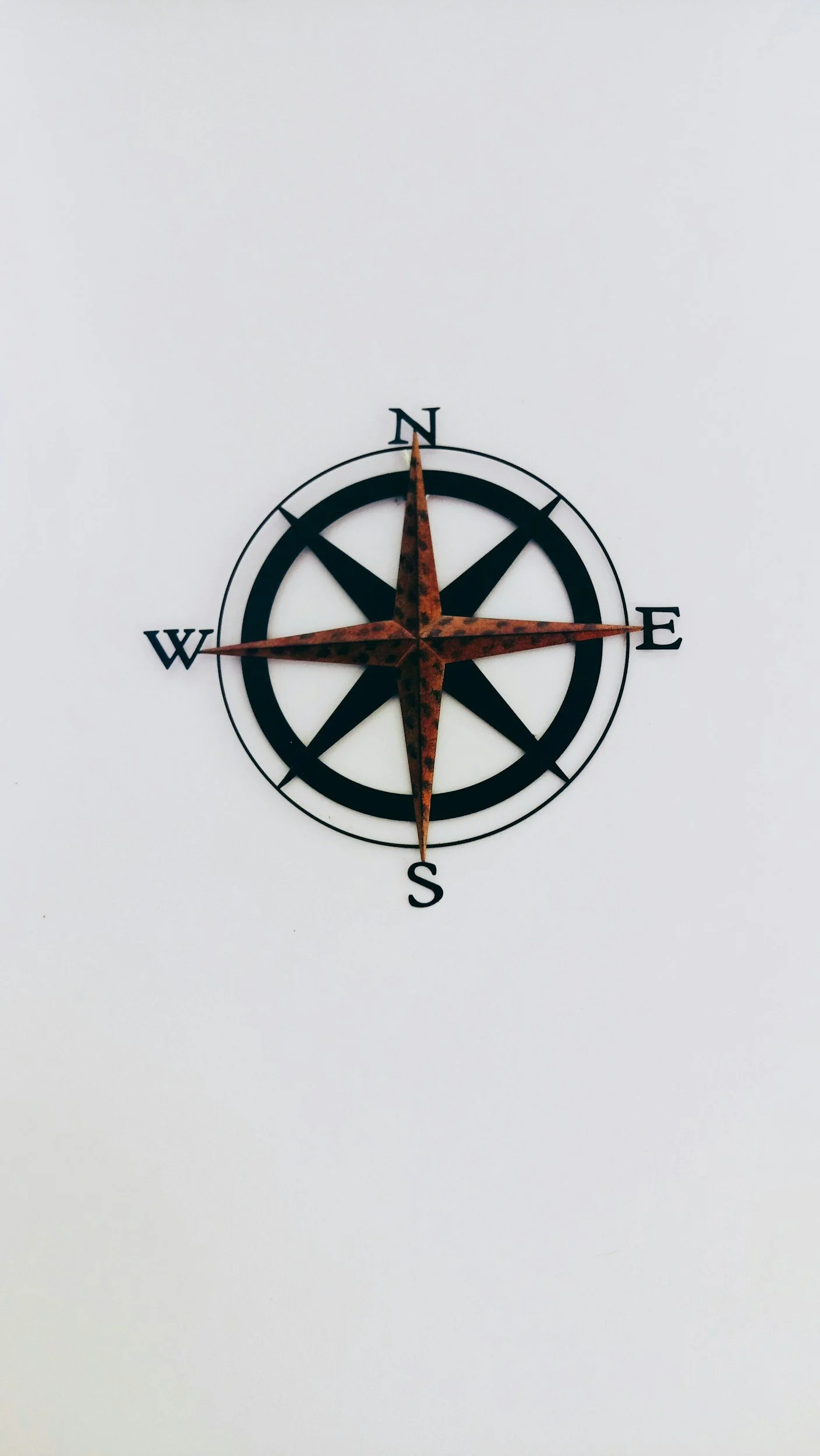 A decorative wall clock designed as a compass rose with a white background.
